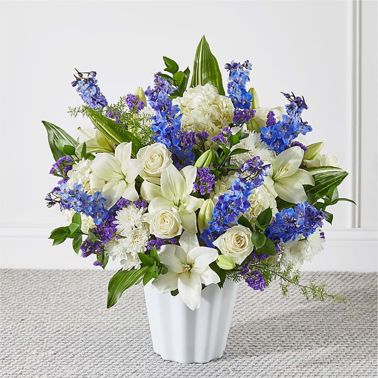 White and blue floral arrangement in a white vase