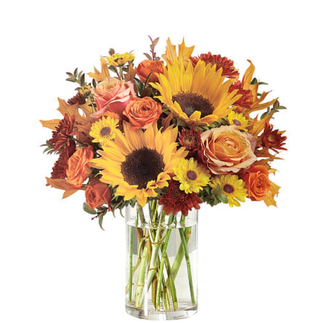 Bouquet of sunflowers, roses, and mums in a clear glass vase