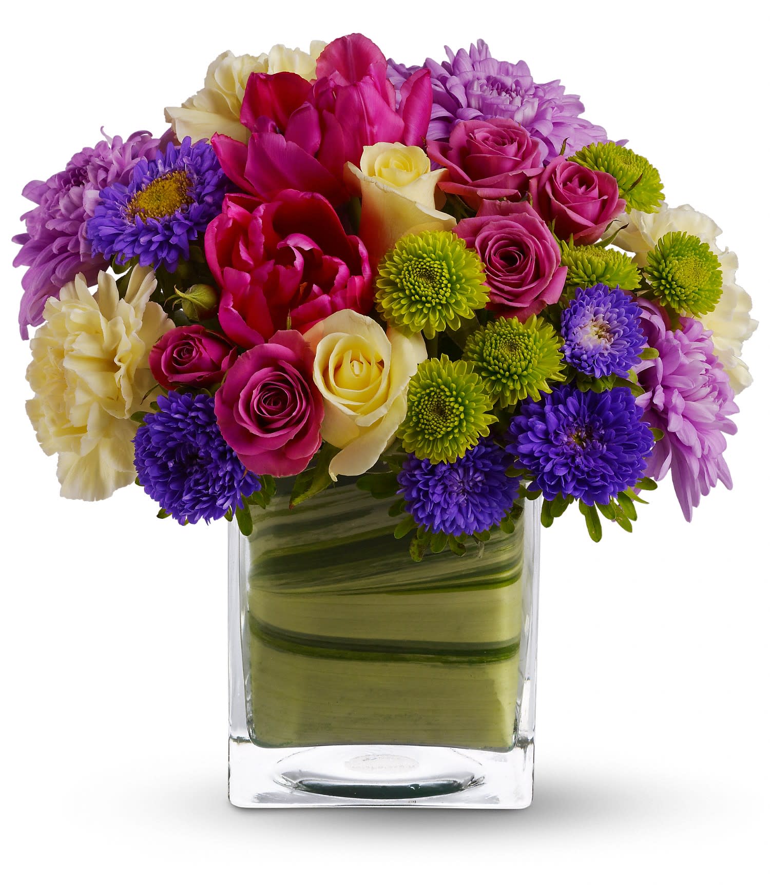 Bright mixed arrangement of pink, purple, and cream flowers in a square glass vase lined with green leaves