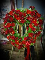 Heart-shaped standing wreath of red flowers with a red ribbon bow on an easel