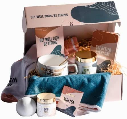 Get well gift box with mug, body products, towel, socks, and bath items arranged in pink packaging.