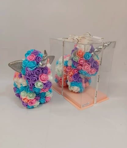 Pastel unicorn-shaped arrangement of artificial roses, one displayed inside a clear gift box.