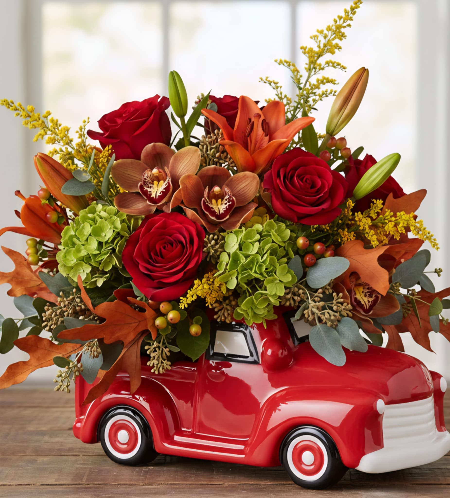 Autumn bouquet of red roses, orange lilies, and green hydrangeas in a red ceramic truck container