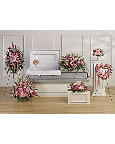 Pink and white funeral flower set with casket spray, standing sprays, and heart wreath around an open casket.