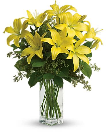 Tall bouquet of yellow lilies in a clear glass rectangular vase