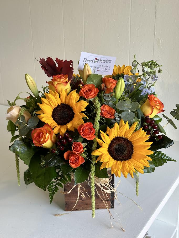 Bouquet of sunflowers and orange roses in a wooden box