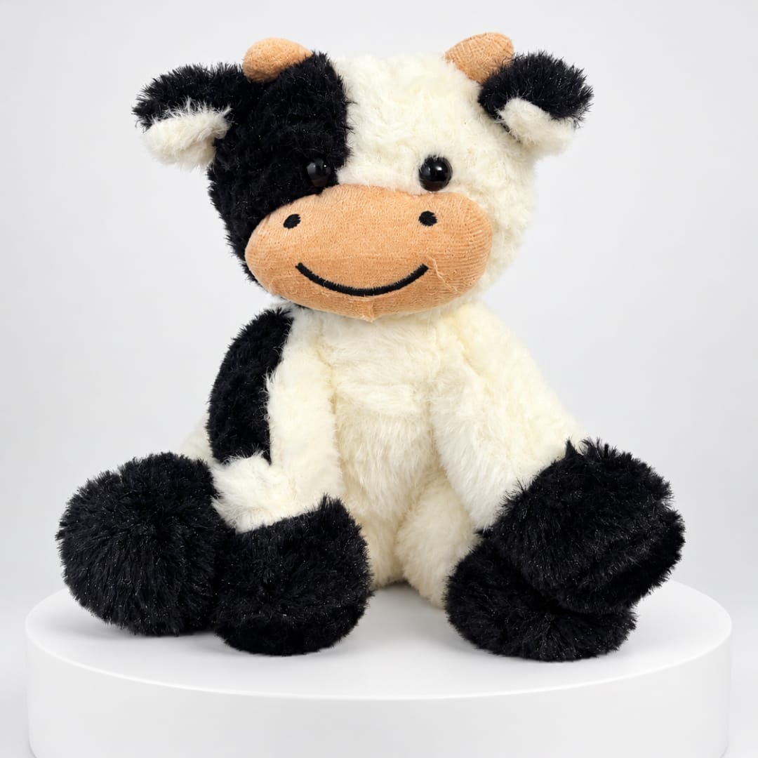 Black-and-white plush cow sitting on a white pedestal