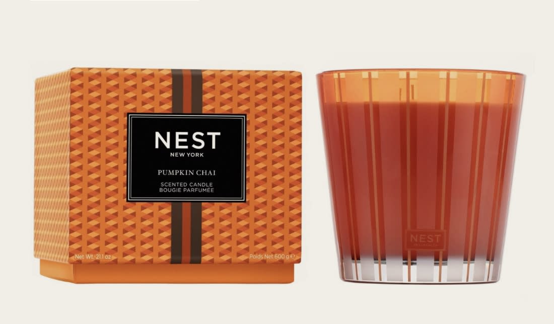 Pumpkin chai scented candle in an orange glass tumbler beside its box