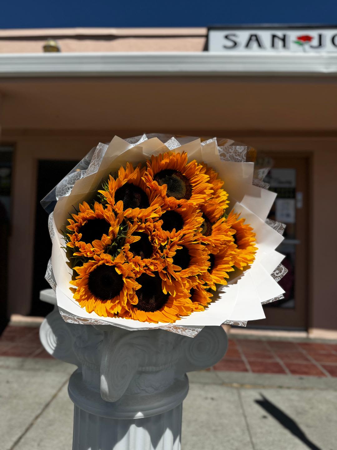Sun-Kissed Bliss Bouquet - A stunning arrangement of vibrant sunflowers, wrapped in crisp white paper, exuding warmth, happiness, and sunshine. Perfect for celebrating special moments or simply brightening someone's day!
