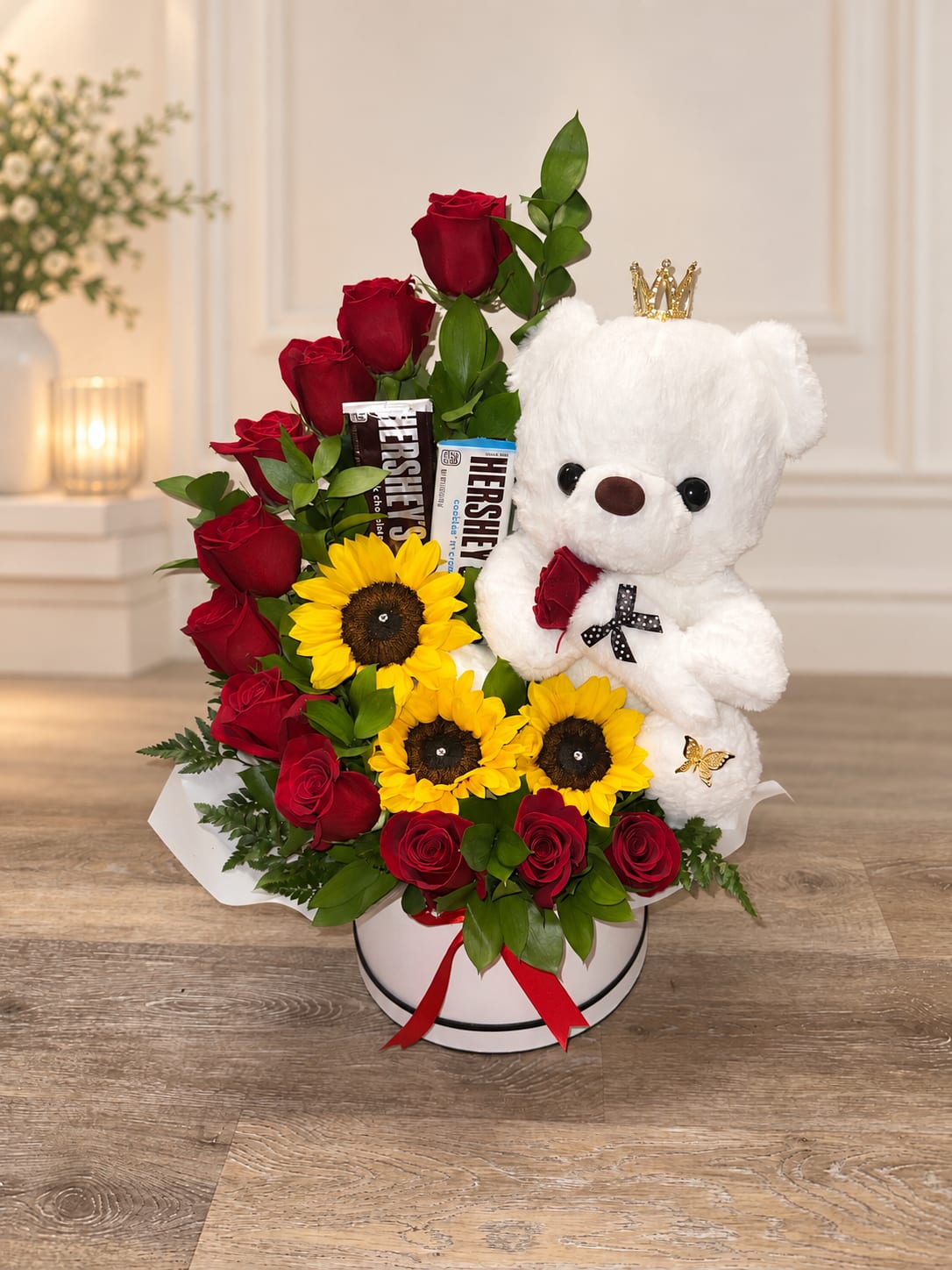 Red roses and sunflowers arranged with a white teddy bear in a round box