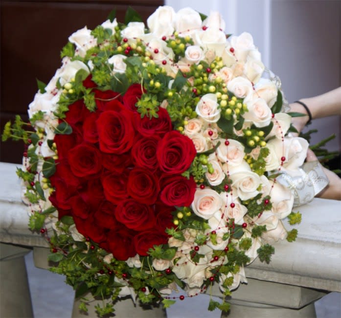 Large bouquet of red and white roses with greenery and berry accents