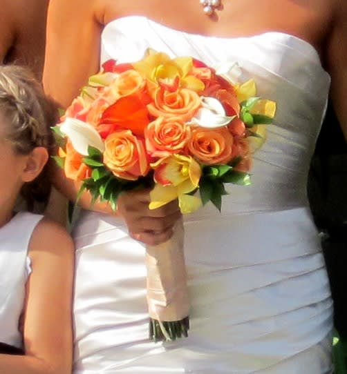 Bride holding a bouquet of orange and yellow roses with white calla lilies