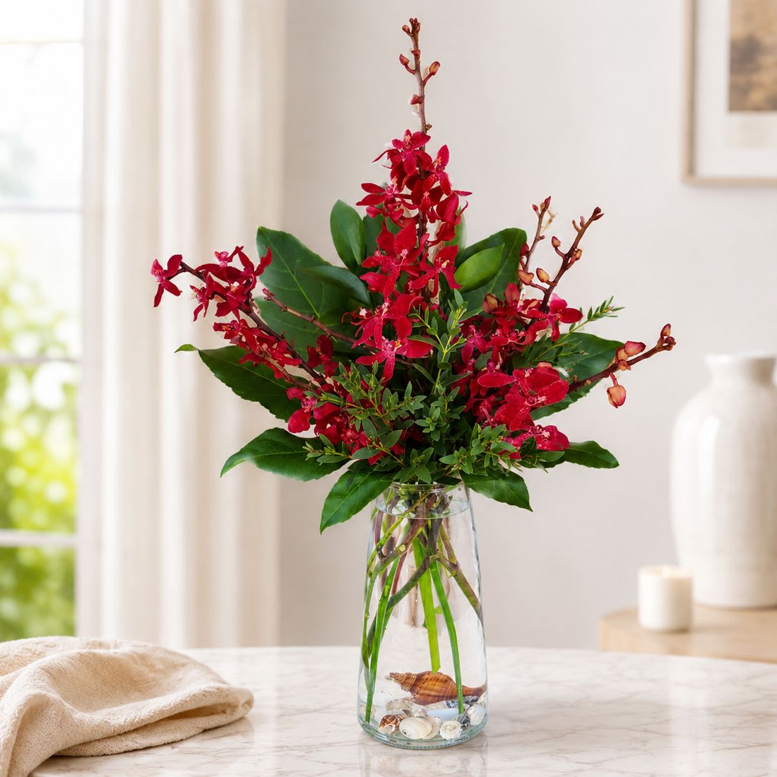 Red Elephant Orchids Vase - Red Elephant Orchids Vase  Simply breathtaking and undeniably rare, this exotic floral statement showcases striking Red Elephant Orchids artfully clustered within dramatic aralia leaves and lush fresh garden greens. Bold yet sophisticated, the rich crimson tones create a powerful visual impact while the sculptural composition adds depth and dimension.  Each arrangement is carefully hand-designed and presented in a sleek designer glass vase, allowing the orchids to stand tall and command attention. This piece is perfect for grand gestures, upscale interiors, or anyone who appreciates extraordinary botanicals.  Standard size measures approximately 7" (W) x 16" (H). Deluxe and Premium versions offer a fuller, more dramatic display with additional orchid stems and larger glass vases.  Available Sizes:  • Standard – 3 Stems of Red Elephant Orchids with Fresh Garden Greens and Aralia Leaf Glass Vase  • Deluxe – 5 Stems of Red Elephant Orchids with Fresh Garden Greens and Aralia Leaves Glass Vase  • Premium – 10 Stems of Red Elephant Orchids with Fresh Garden Greens and Aralia Leaves Glass Vase  Dramatic, modern, and unforgettable, Red Elephant Orchids Vase is a true expression of refined tropical luxury.