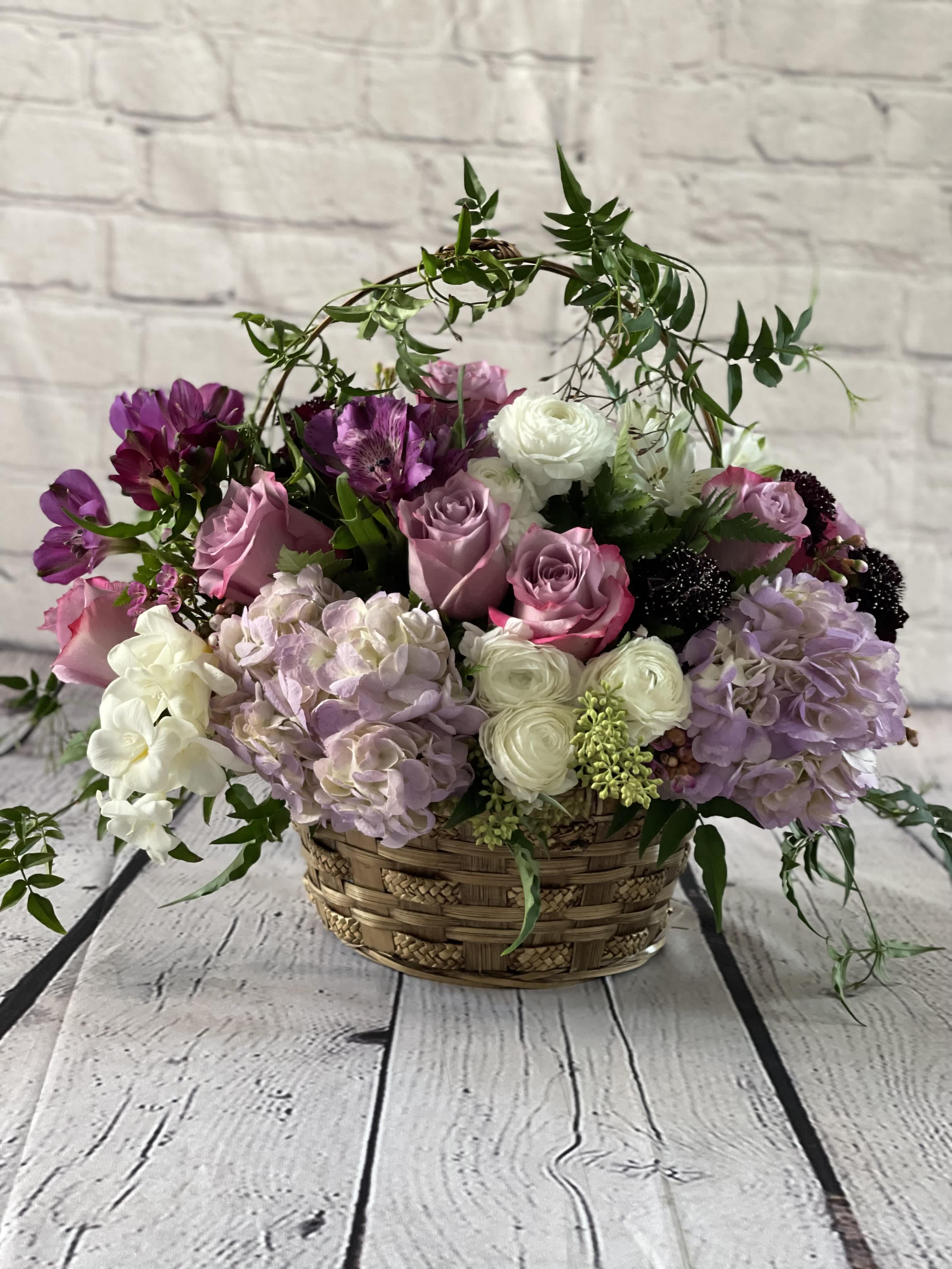 Basket arrangement of pink, white, and purple flowers