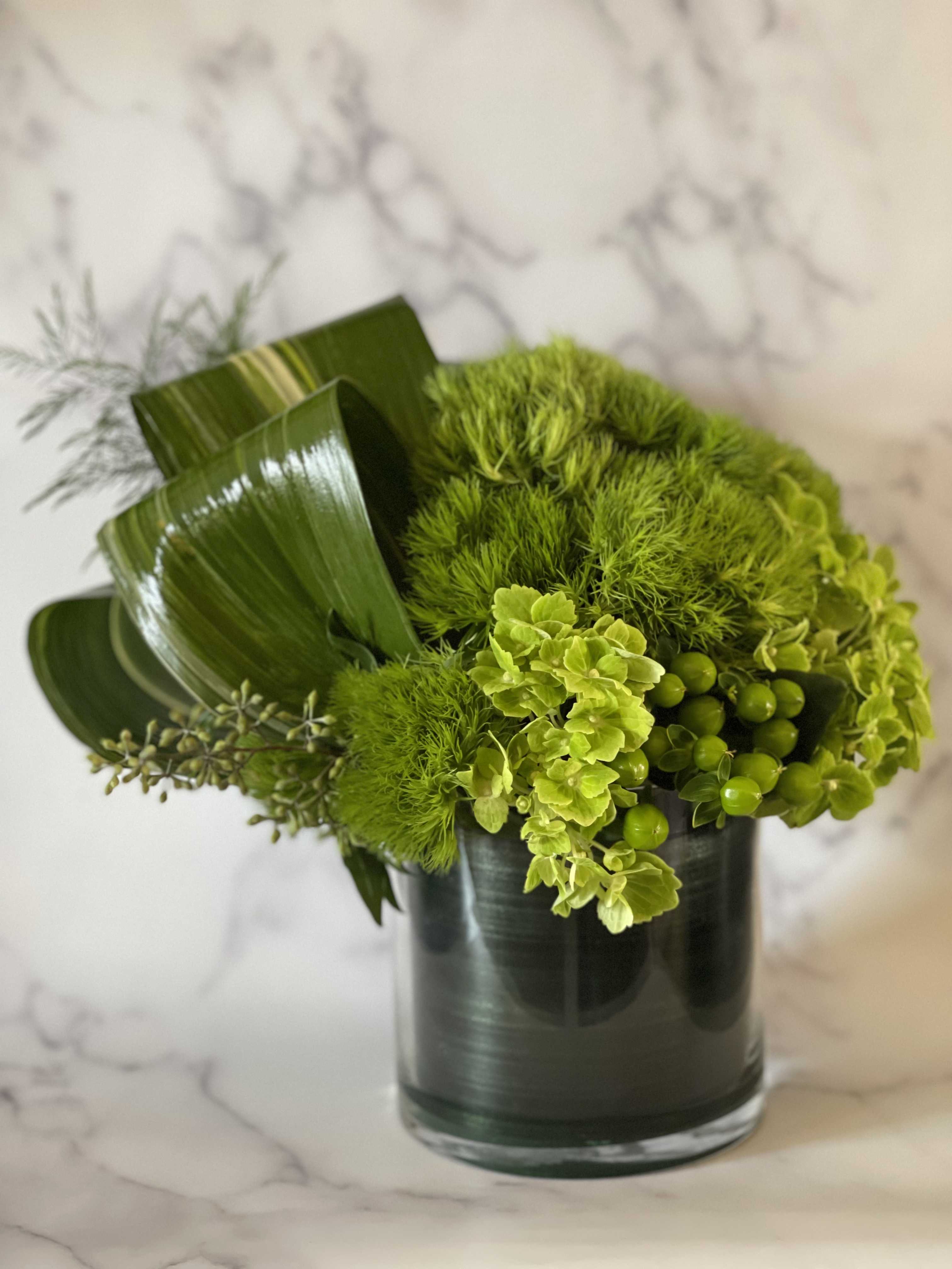 Green floral arrangement in a dark glass vase
