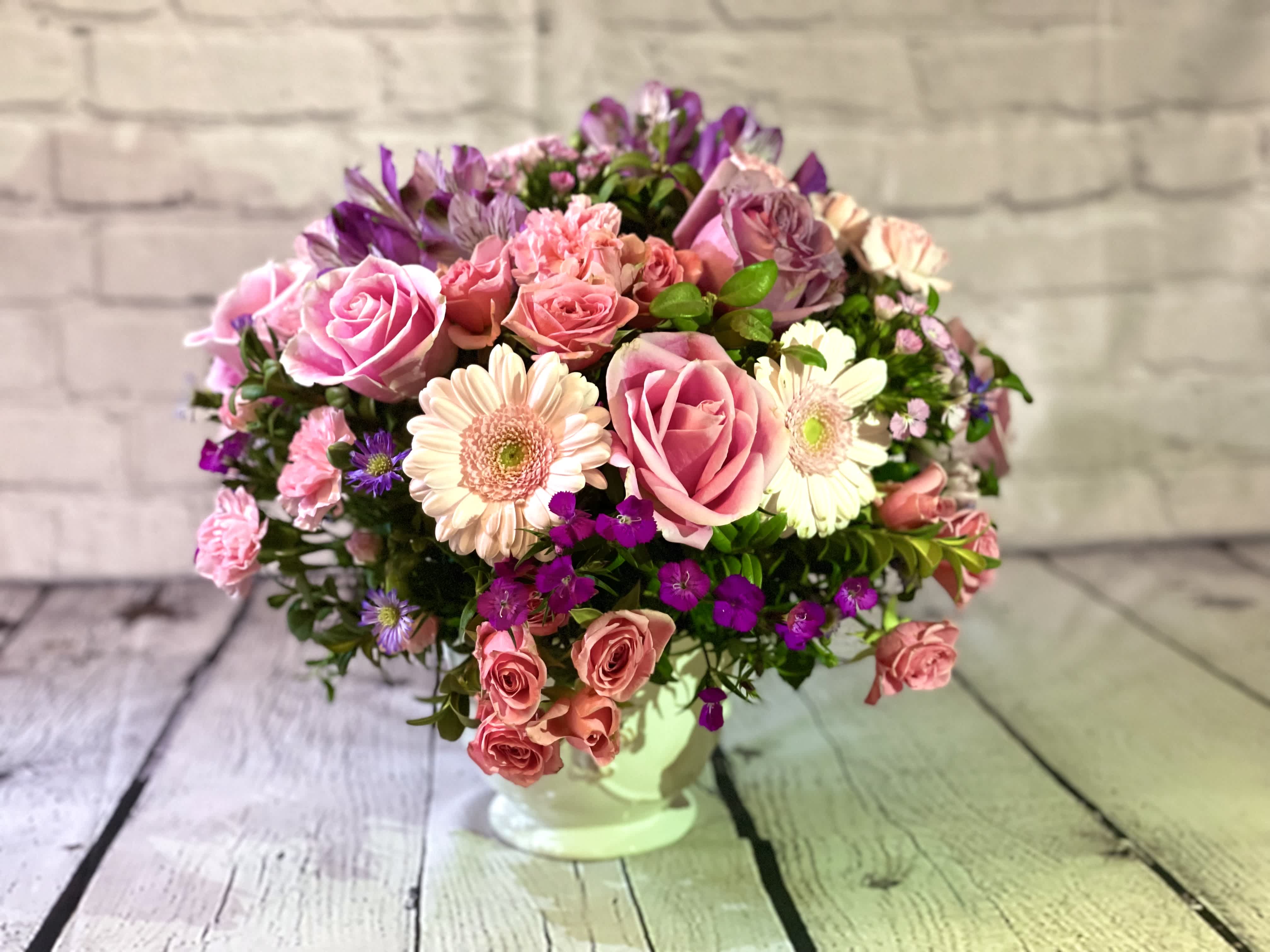 Pink and purple mixed flower arrangement in a white vase