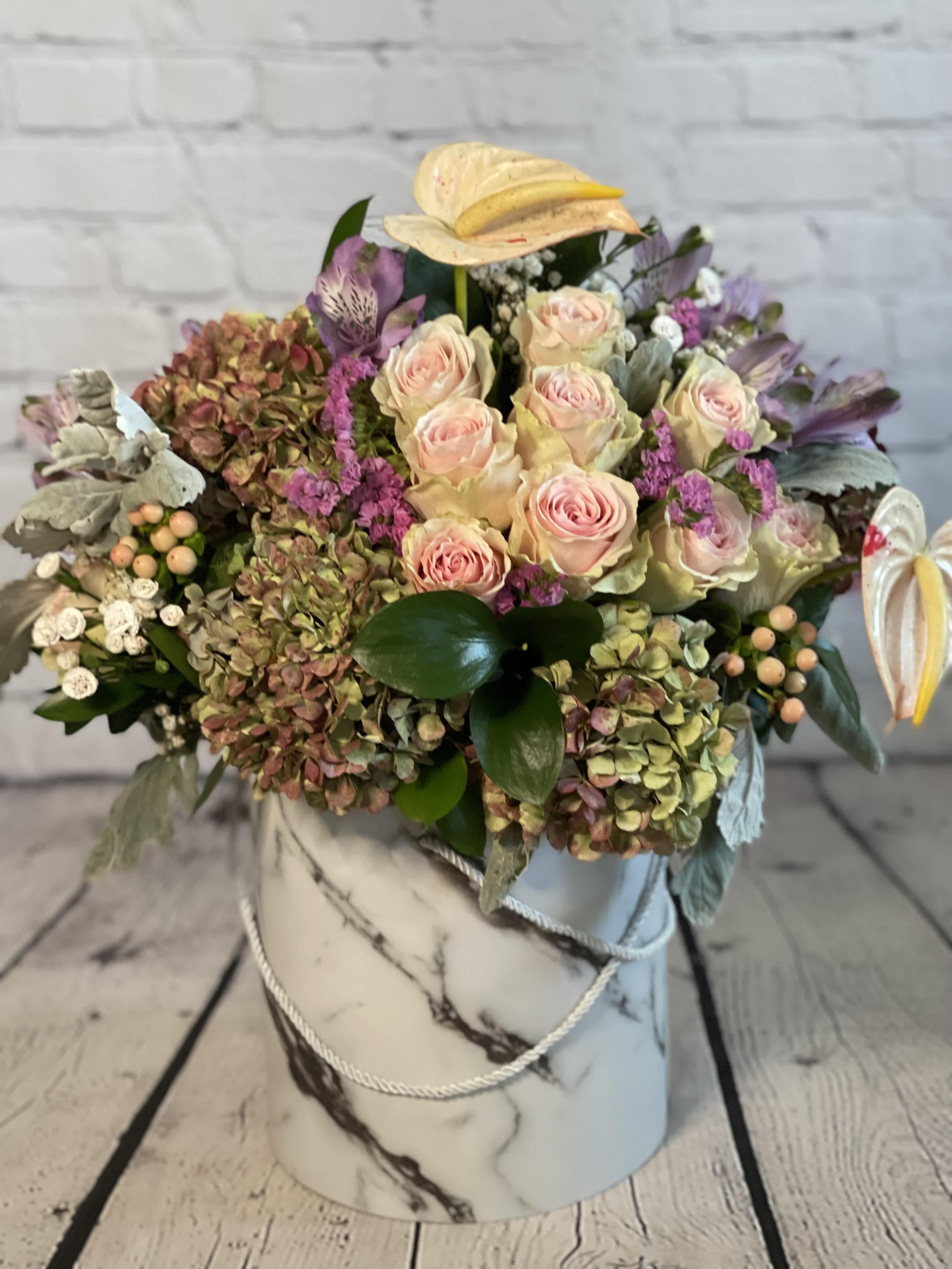 Mixed bouquet of pale pink roses and hydrangeas in a marble-patterned hat box