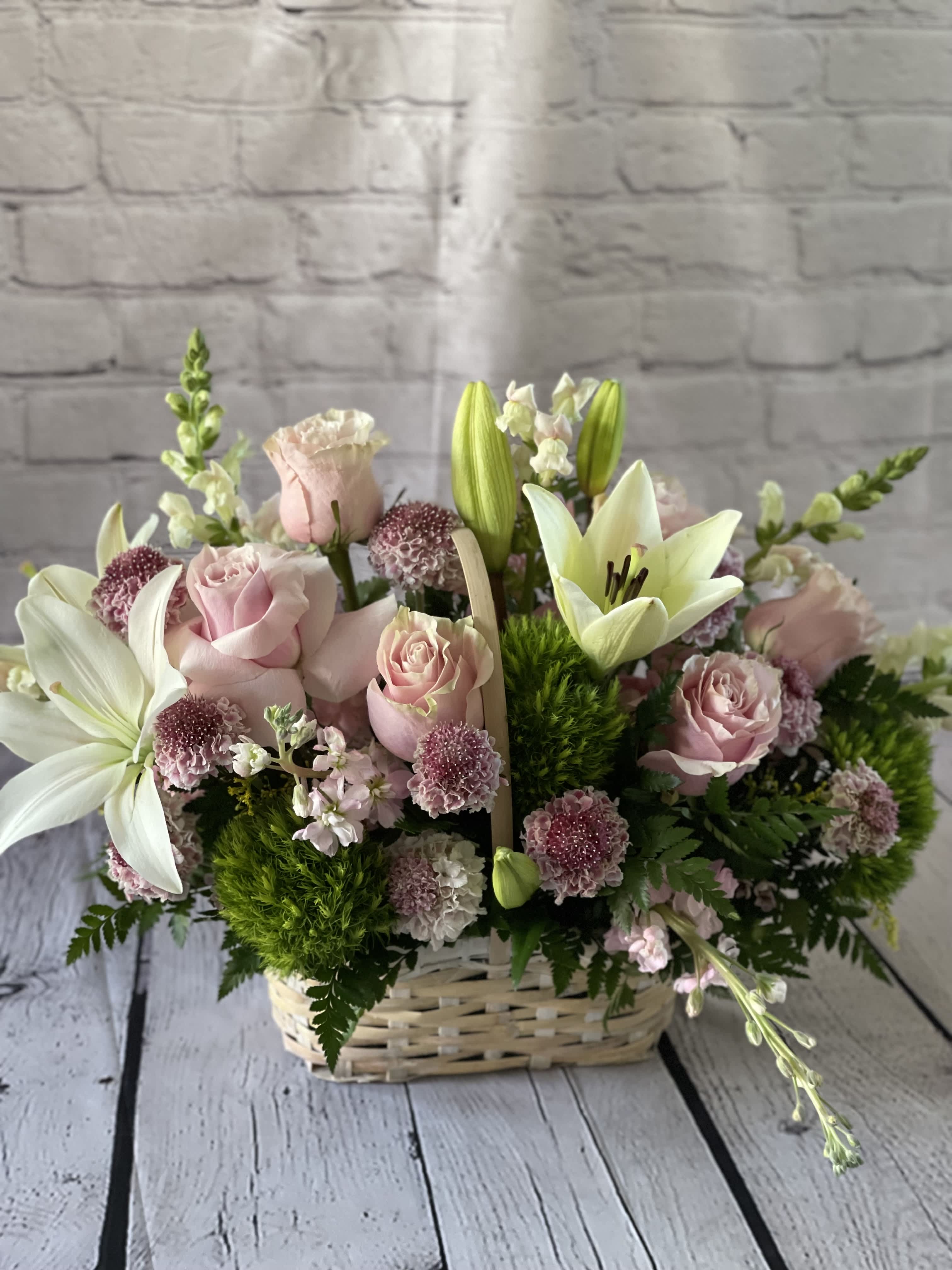 Pink roses and white lilies arranged in a wicker basket