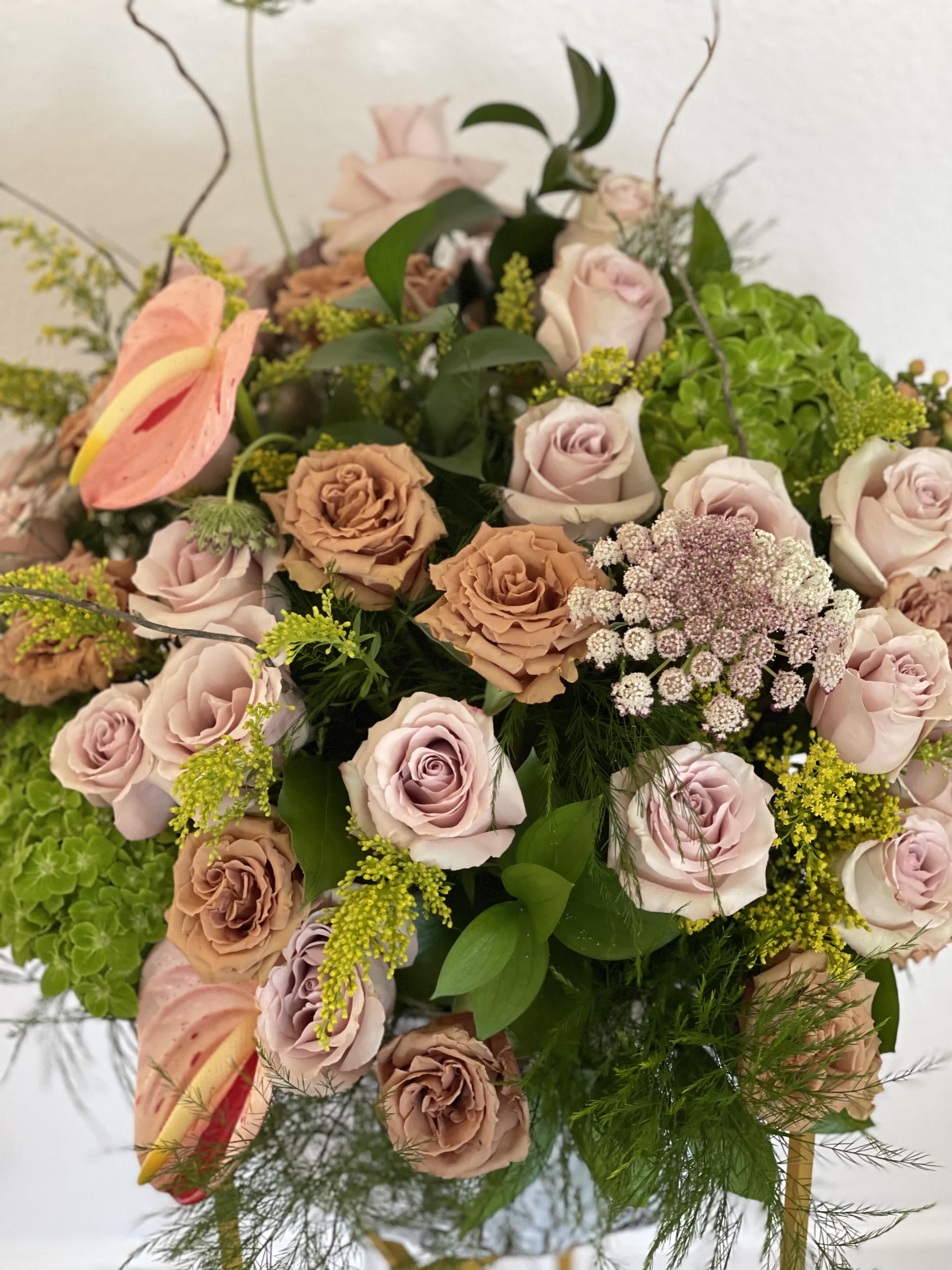 Bouquet of blush and tan roses with pink anthuriums and green filler