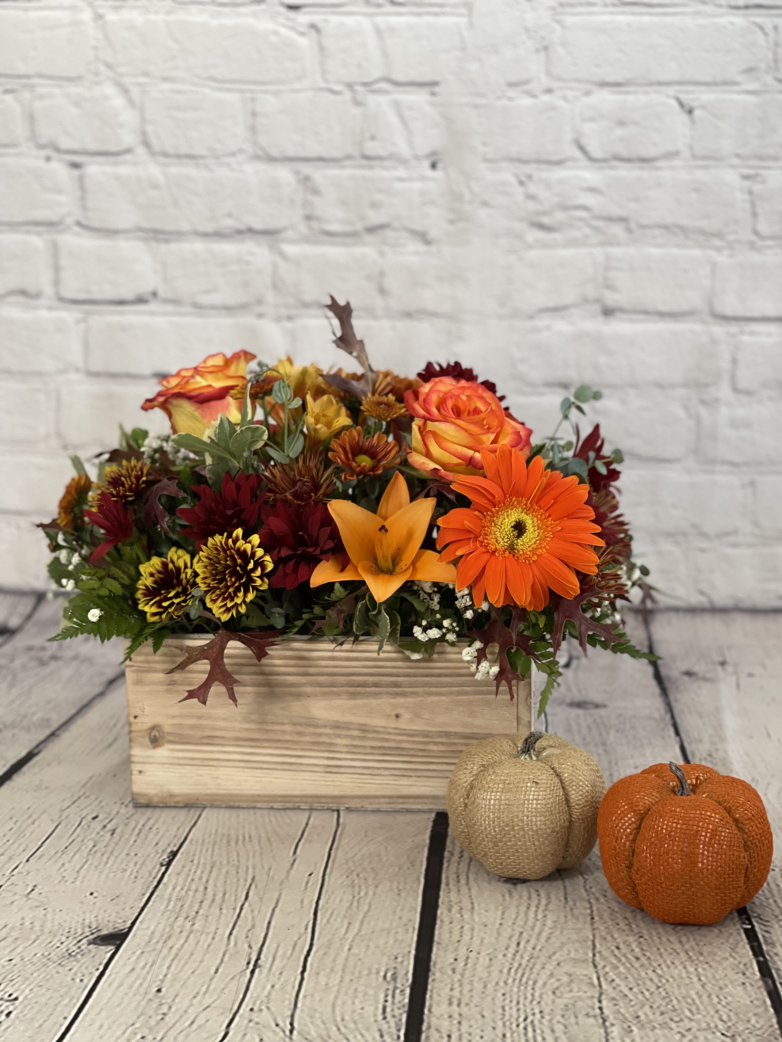 Woodland Harvest - The Woodland Harvest floral arrangement is a striking tribute to the autumn season, featuring an assortment of beautiful lilies, roses, gerberas, and chrysanthemums arranged in a charming wooden box. The warm and rich autumn hues of the flowers provide a sense of elegance and the wooden box adds a rustic charm to the piece, evoking a sense of serenity and connection to nature. Ultimately, the Woodland Harvest arrangement is a perfect tribute to the fall season and will bring feelings of joy to anyone who receives it.