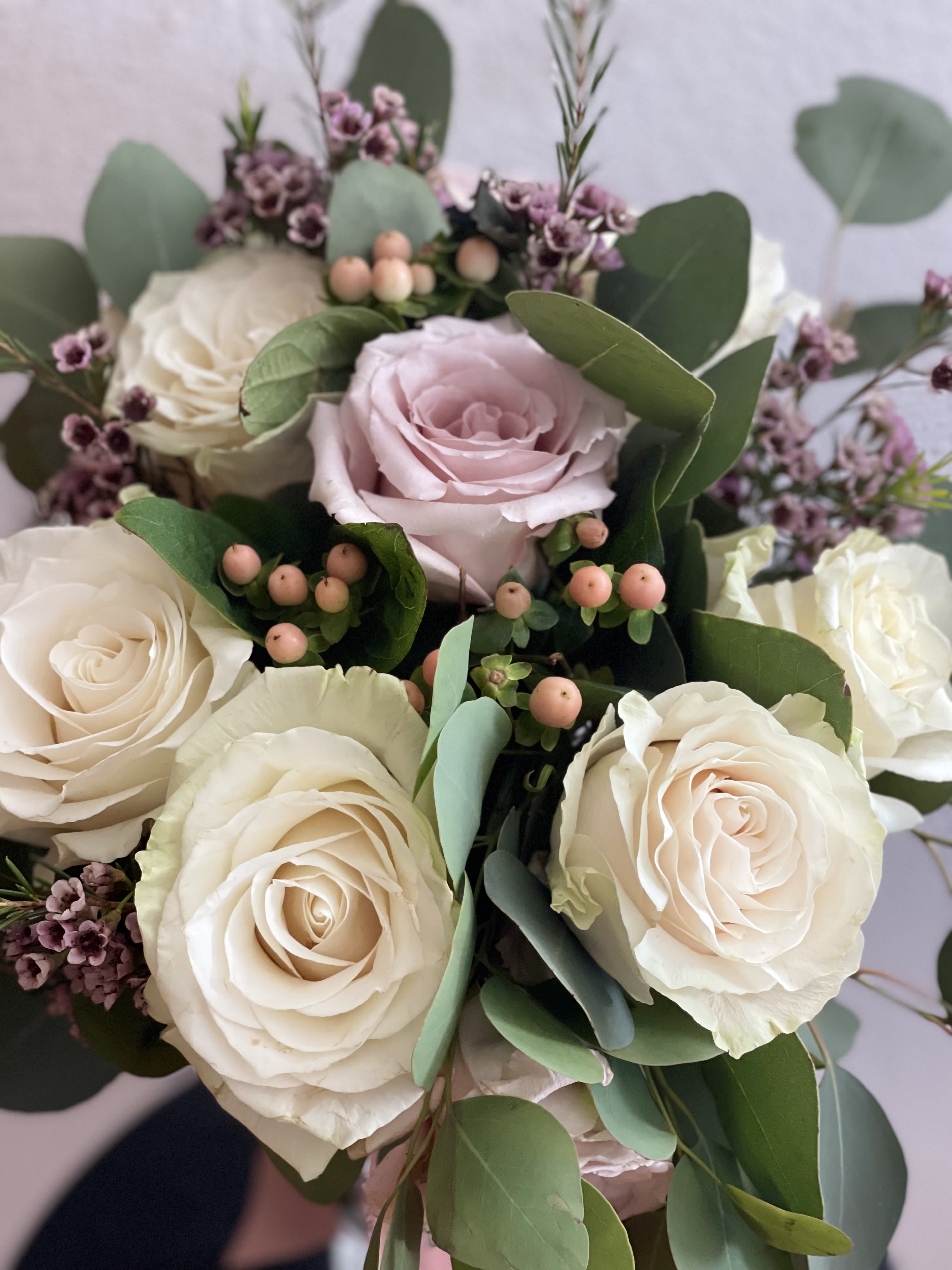 Bouquet of cream and blush roses with eucalyptus and small purple filler flowers