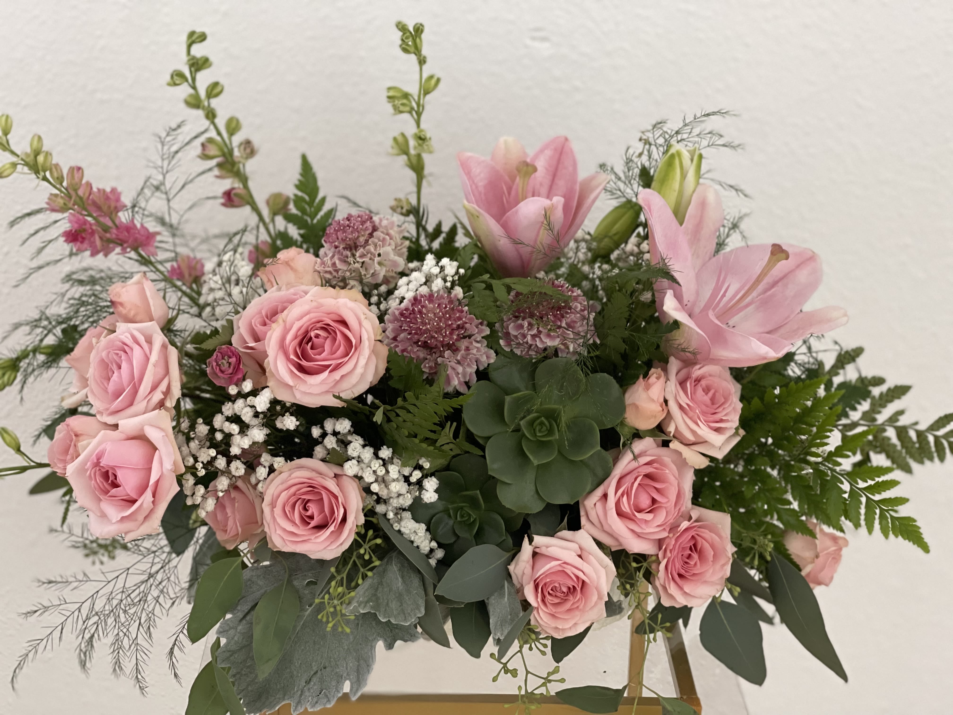 Pink roses and lilies arranged in a low vase with greenery