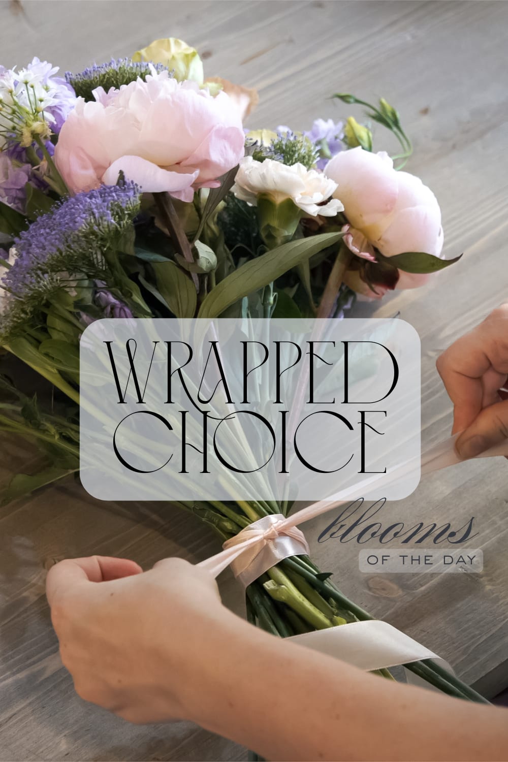 Wrapped bouquet of pale pink and lavender flowers tied with a satin ribbon