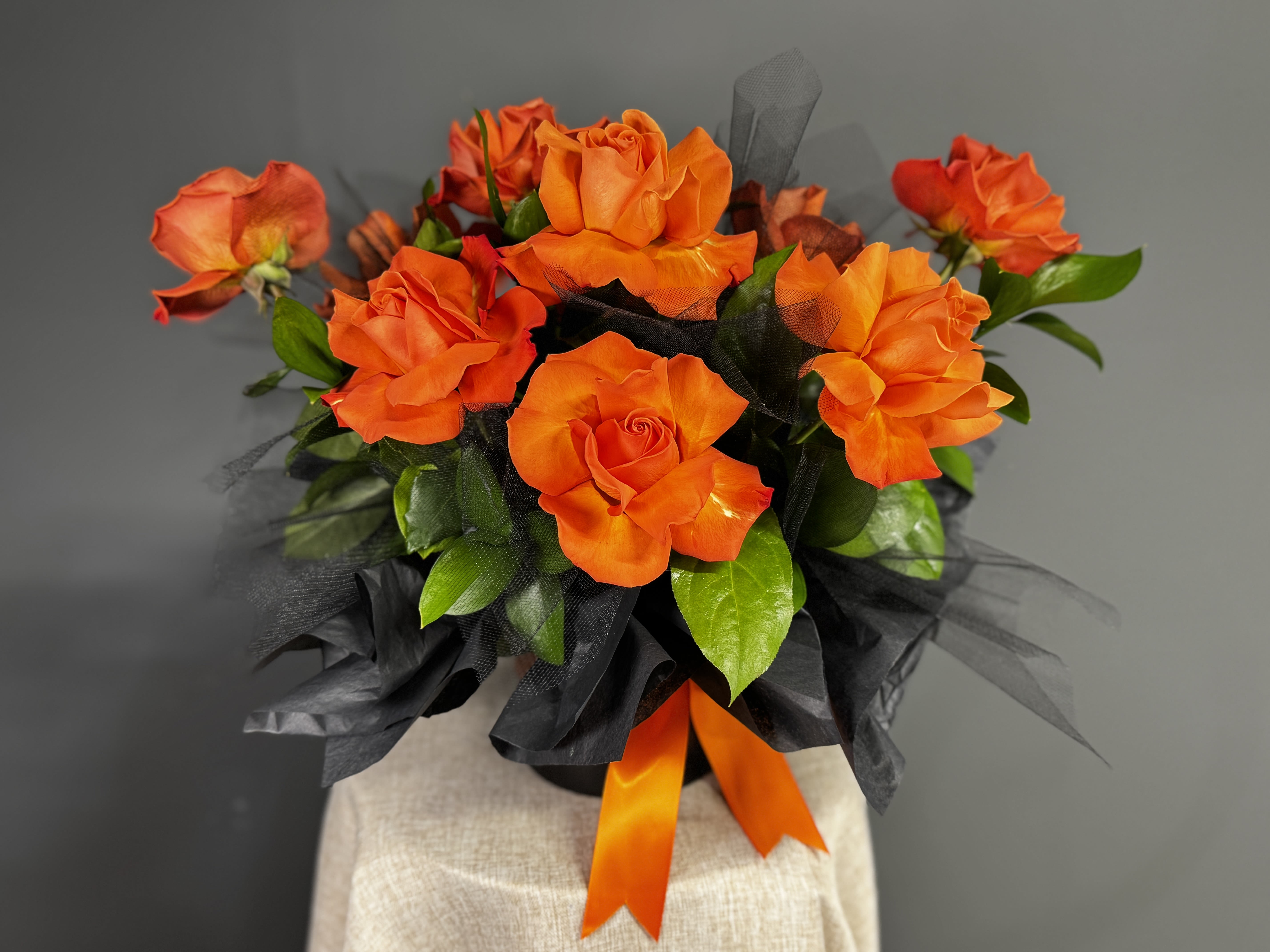 Orange roses arranged with black wrap and ribbon