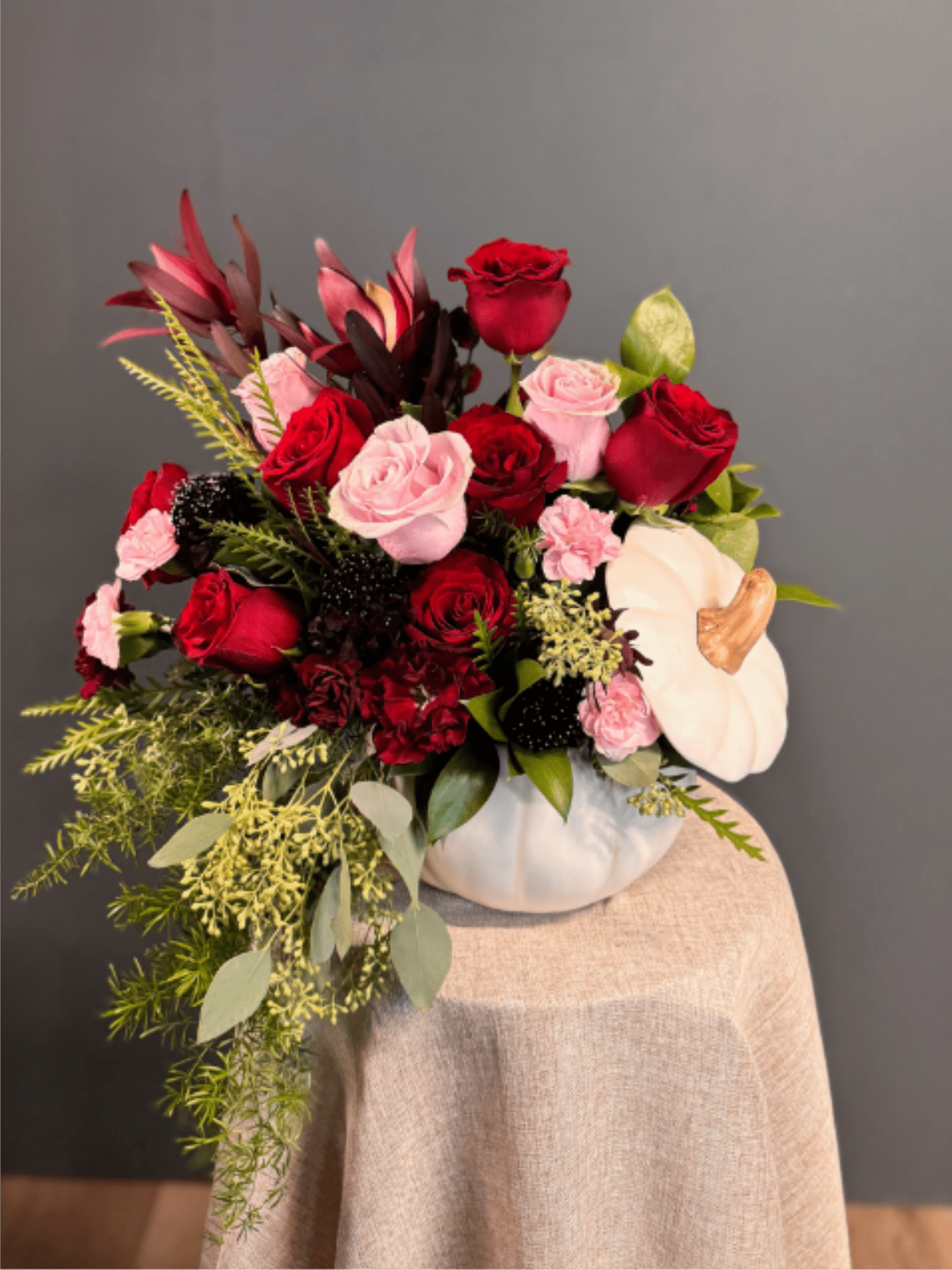 Autumn Elegance - A sophisticated mix of deep red and blush blooms, artfully arranged in a chic white pumpkin vase. Perfect for adding seasonal charm with a romantic twist.