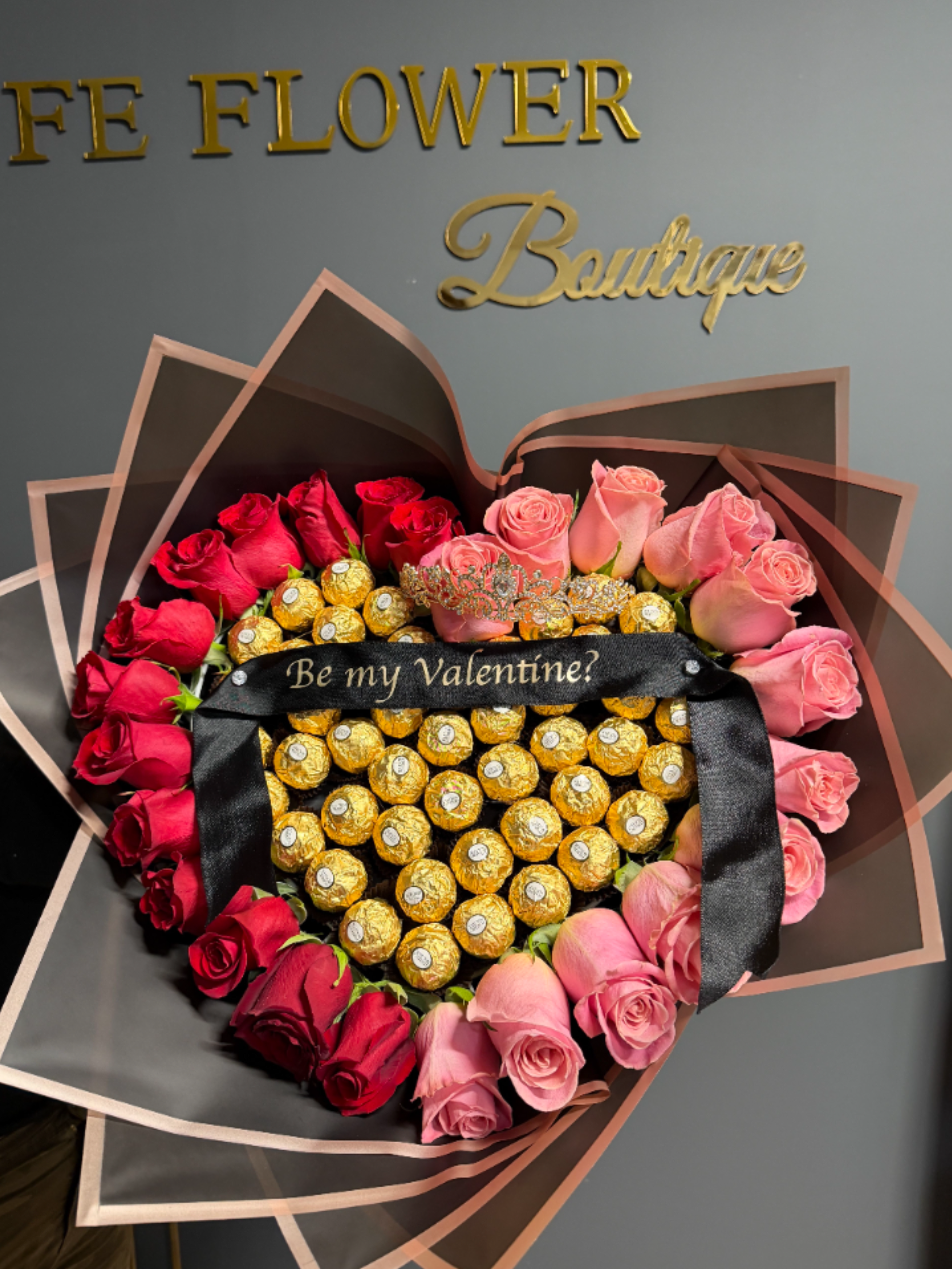 Be Mine Chocolate Heart - Be Mine Heart is a show-stopping heart-shaped wrapped bouquet designed to captivate at first sight. Lush, hand-selected blooms are artfully arranged and paired with luxurious Ferrero chocolates, creating the perfect balance of romance and indulgence. Wrapped with care and elegance, this bouquet is a heartfelt way to say “I love you,” “I’m thinking of you,” or “Be mine,” a sweet and unforgettable gift for life’s most romantic moments.  * Ribbon not included*