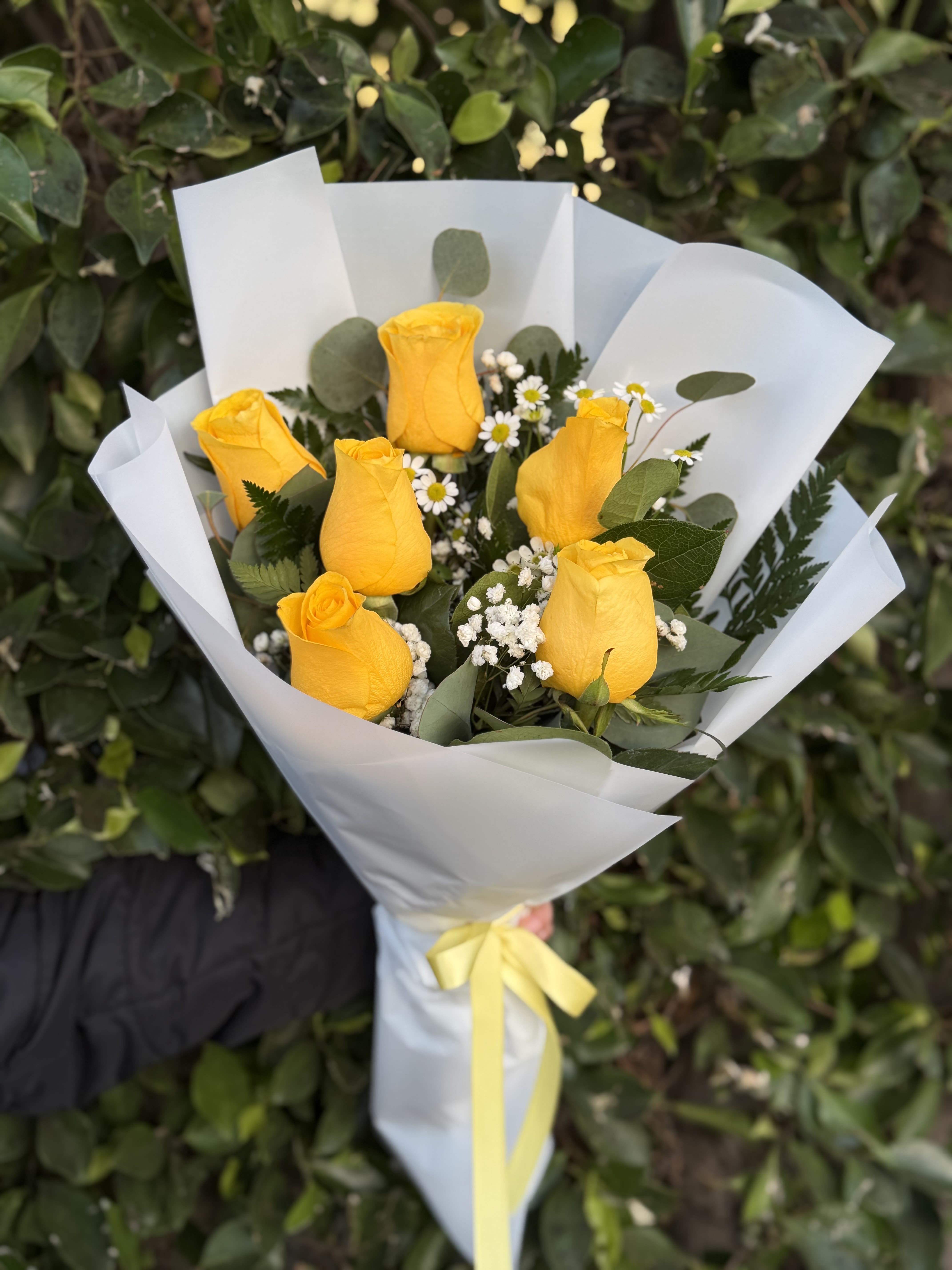 Golden Glow- 6 - Bright, happy, and full of charm—this wrapped handheld bouquet features 6 vibrant yellow roses accented with airy textures and fresh greens. Designed to feel light and uplifting, it’s the perfect way to share joy, appreciation, or a simple “thinking of you.”