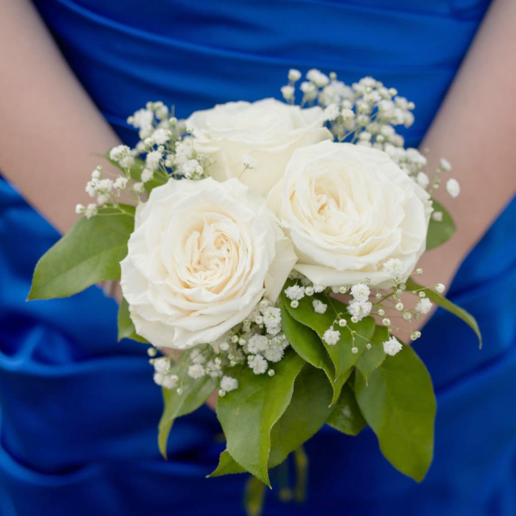 Marseille - Three roses gathered in a hand-tied nosegay create a compact, elegant prom bouquet that feels both timeless and fresh. The roses sit at the center so the person you're celebrating will look poised and photographed perfectly, while airy clusters of tiny white filler flowers soften the arrangement and add delicate texture. Looking for a color other than white?  Select yellow, orange, pink, red or lavender by requesting it in special instructions during check out.  Deep green foliage frames the blooms and extends just beyond the petals for a clean silhouette that's easy to hold. This petite arrangement is ideal for prom, small ceremonies &amp; romantic gestures- it's the kind of bouquet that makes someone feel seen and special.   Pickup dates for prom are Saturday, April 11th, 18th, 25th and May 2nd; please call if you need this for a different date.