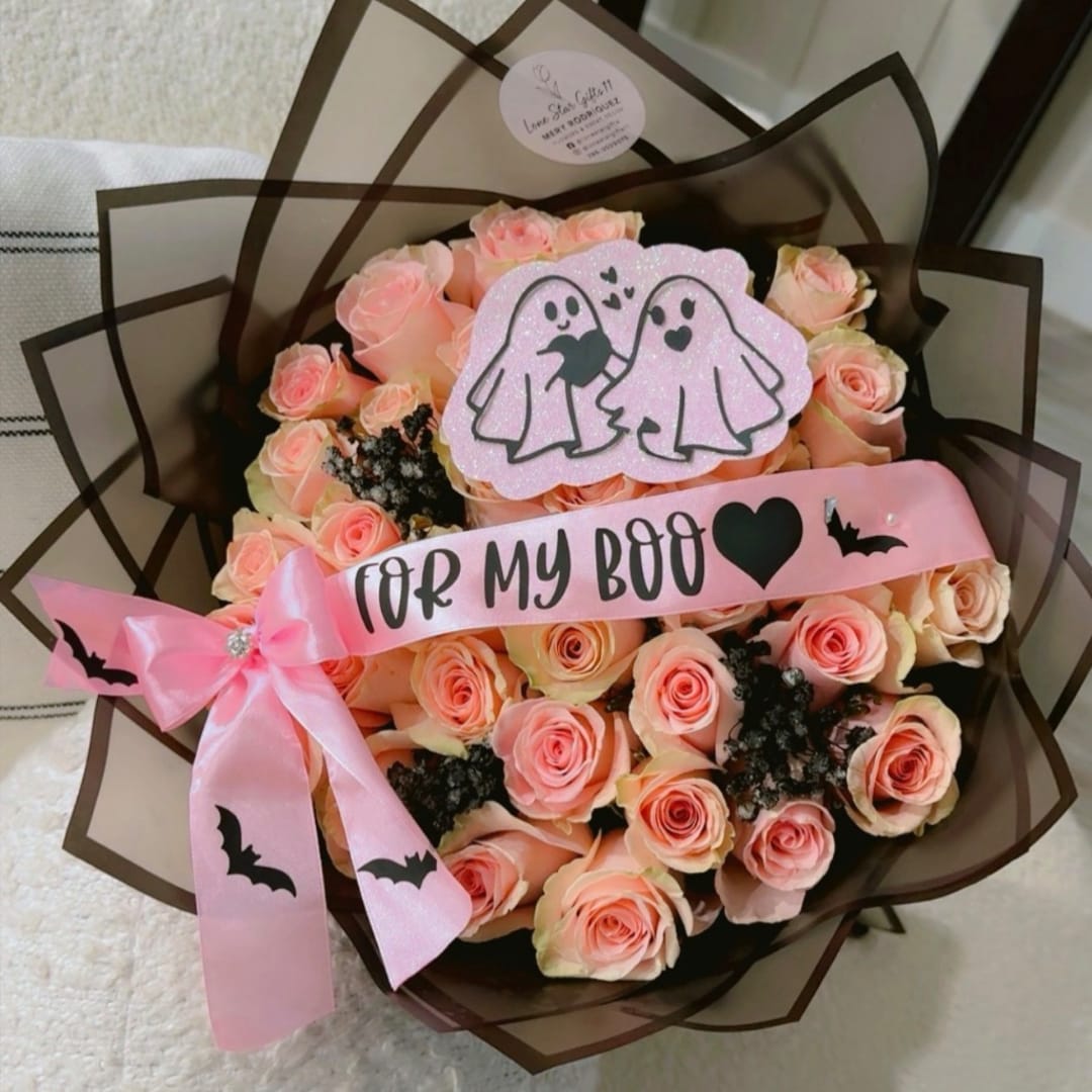 Bouquet of peach-pink roses with a pink ribbon and Halloween decorations