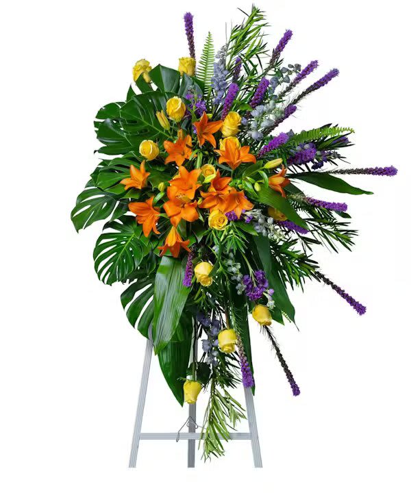Birds of Solace Grand Sympathy Spray - The Birds of Solace Standing Spray will capture the spirit of joy your loved one brought to life with bright blooms such as yellow roses, orange lilies, purple liatris, and lavender delphinium nestled into a lush mixture of tropical foliage like monstera and podocarpus. Appropriate for funerals and graveside services.