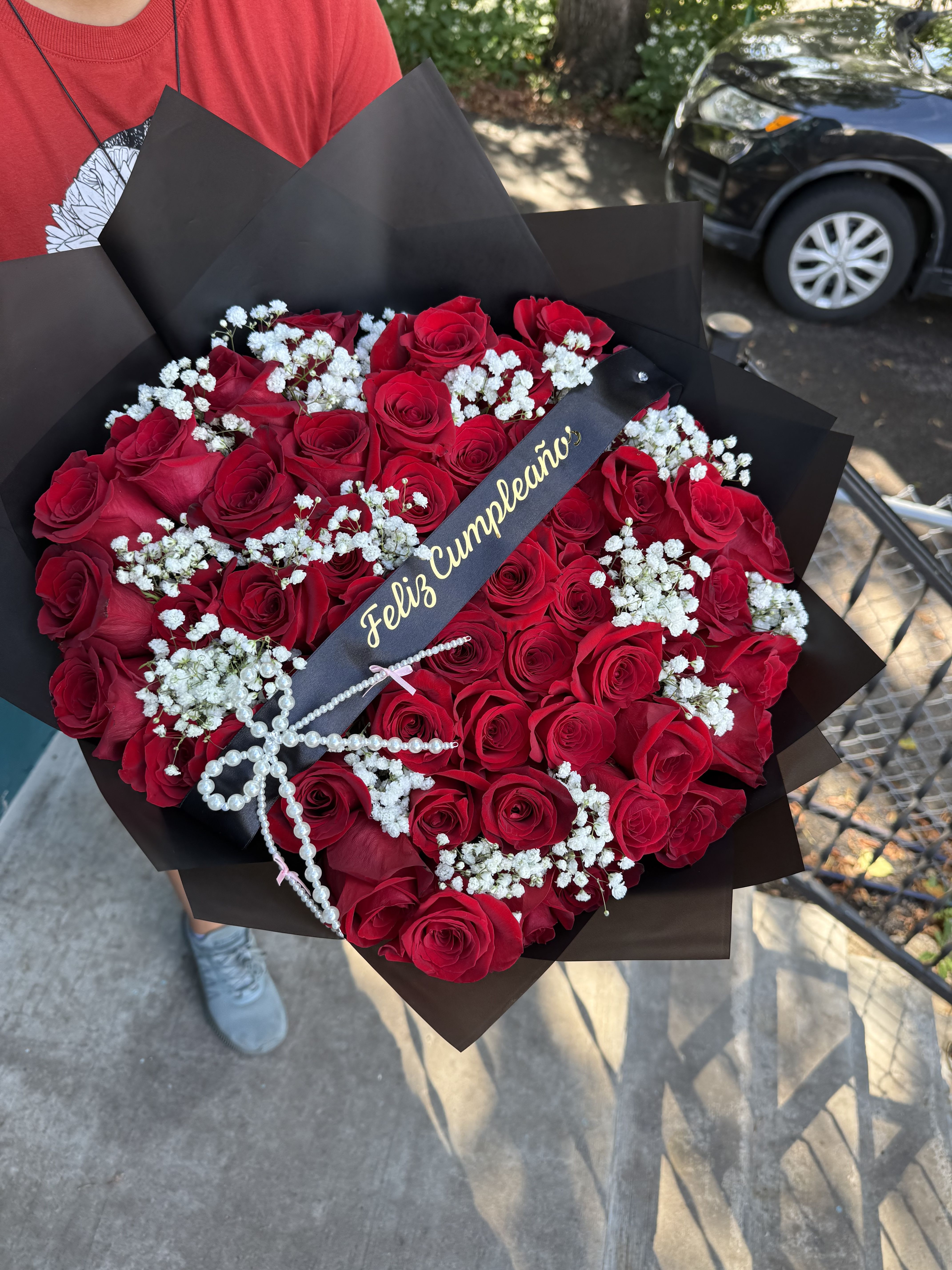 Bouquet of red roses with white baby's breath in black wrap