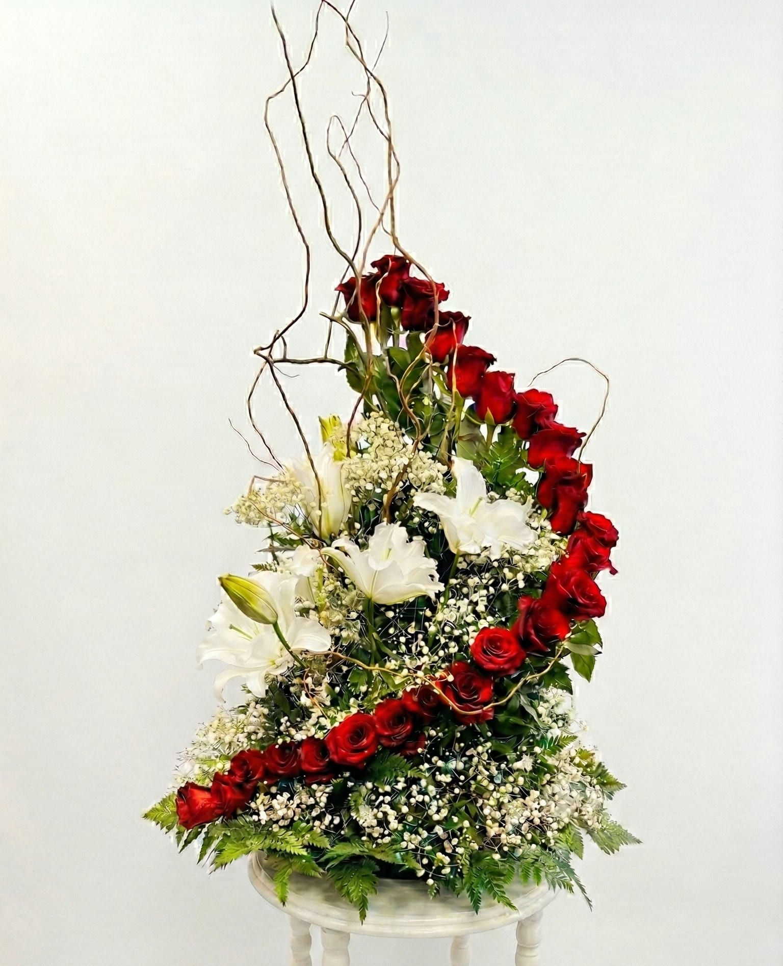Tall arrangement of red roses and white lilies on a pedestal stand