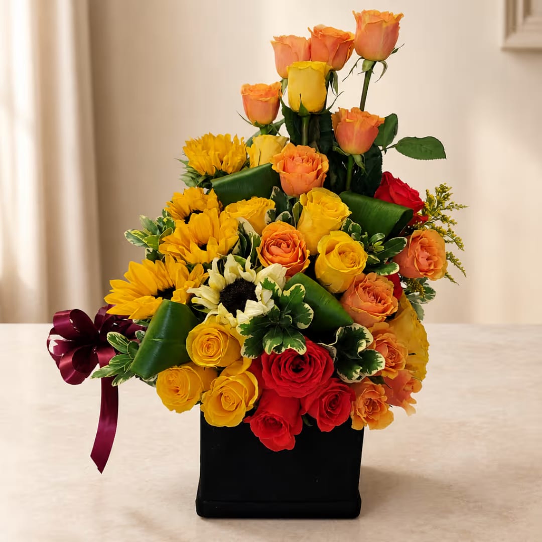 Mixed bouquet of roses and sunflowers in a black box with a burgundy ribbon