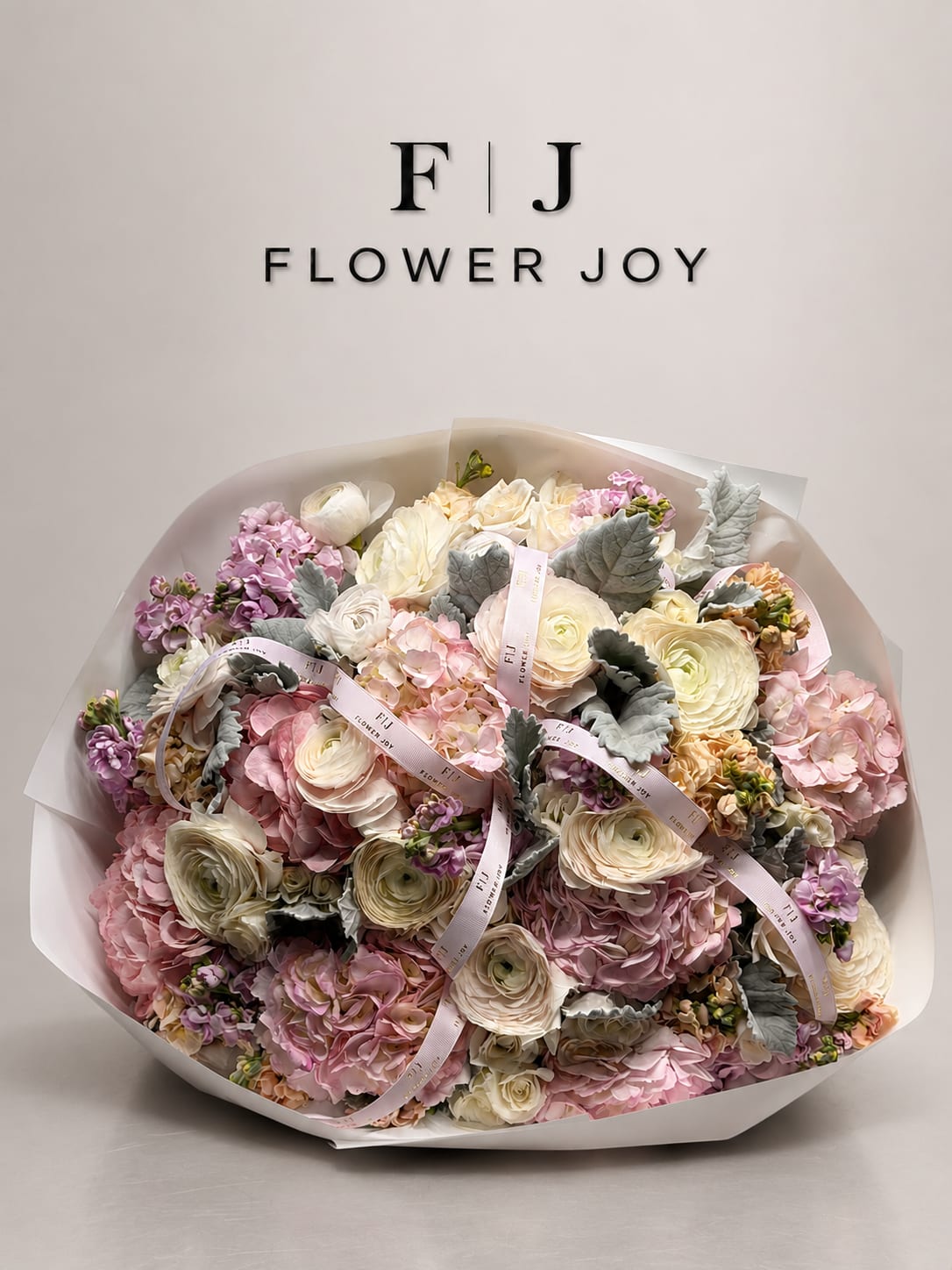 Large pastel bouquet of pink, cream, and lavender flowers wrapped in white paper