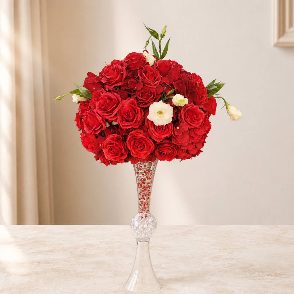 Red rose arrangement in a tall clear vase with a few white blooms