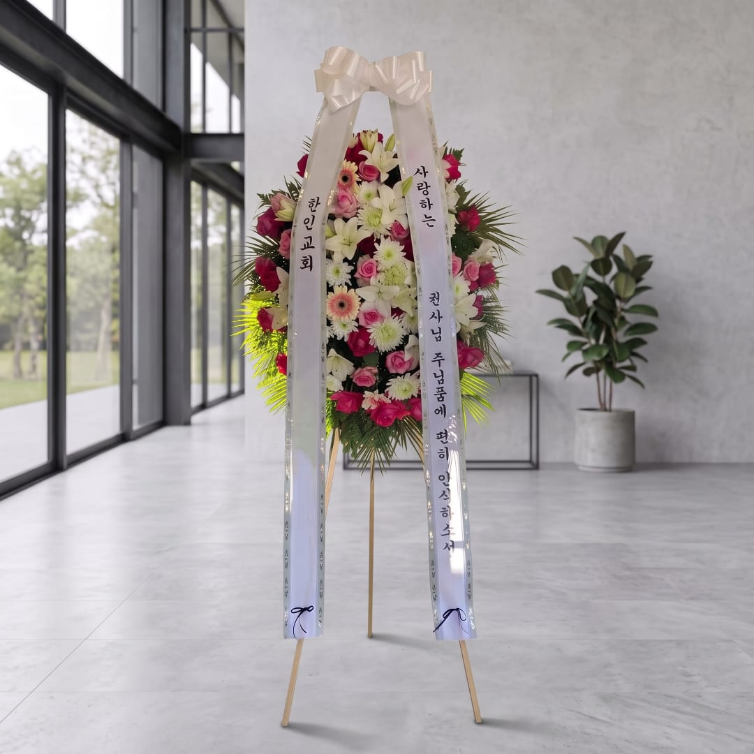 Tall standing floral wreath with pink and white flowers and white ribbons