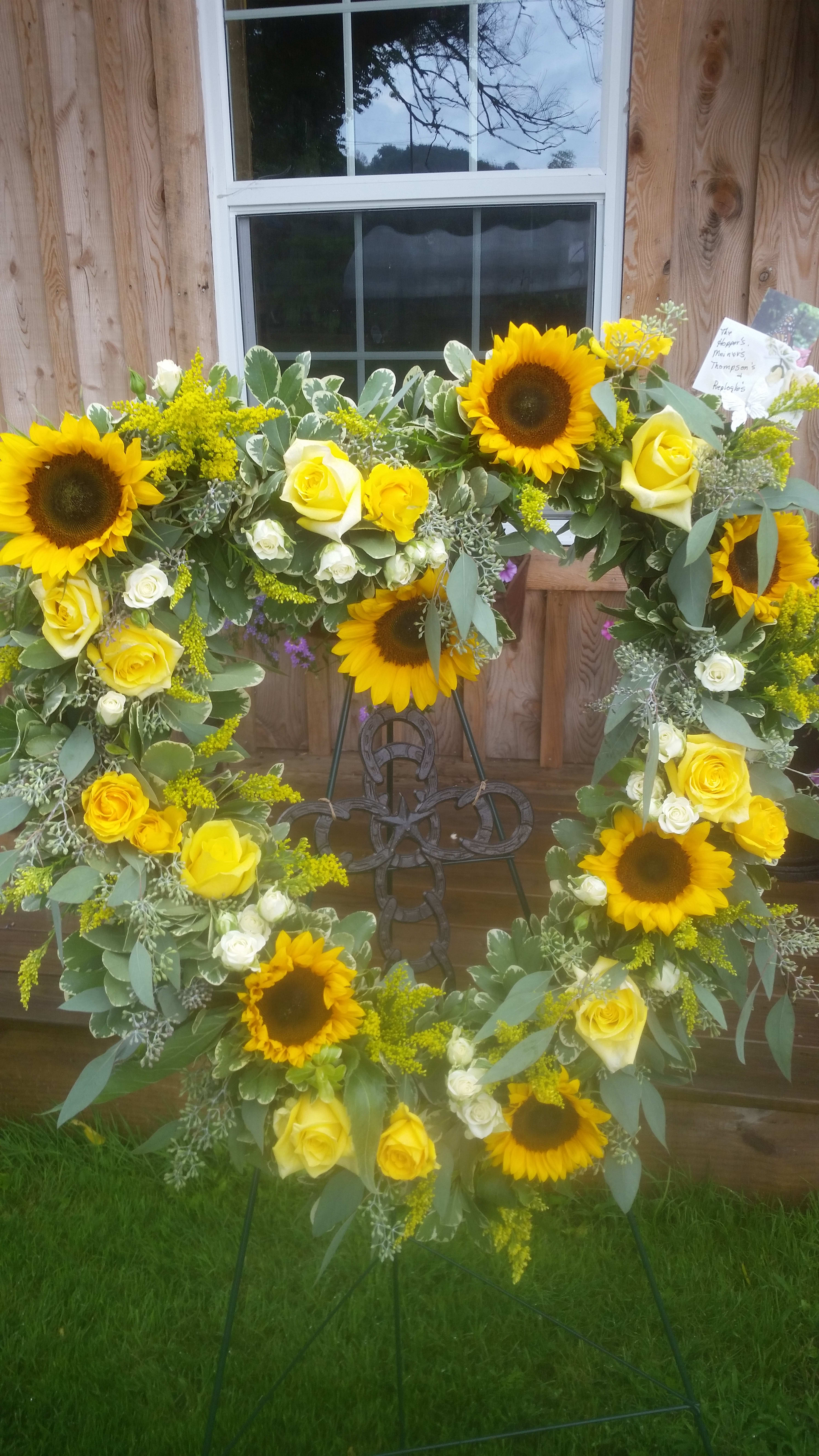 Sunflower and yellow rose wreath on a metal stand