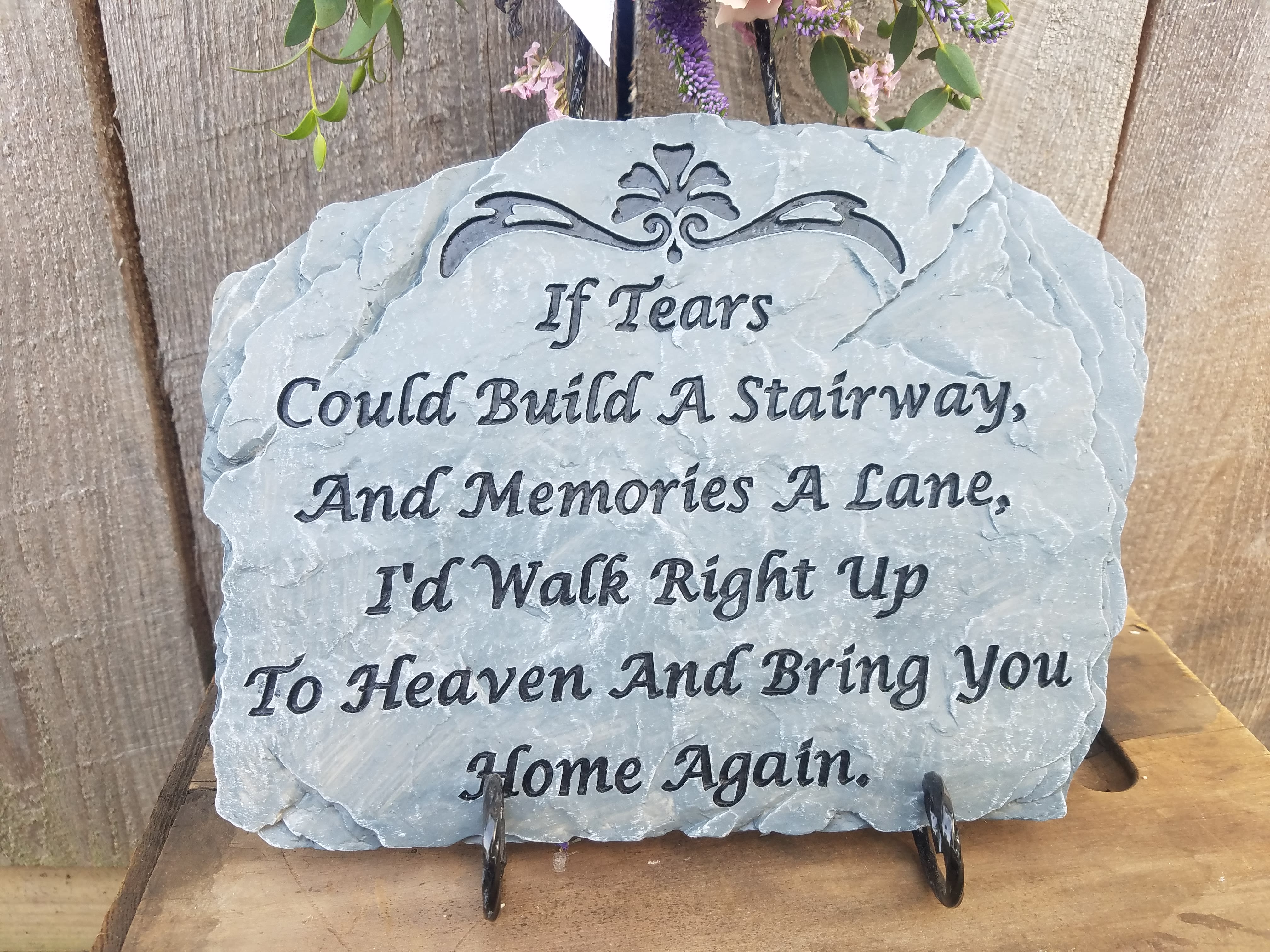 A memorial stone plaque with a sympathy quote on a stand.