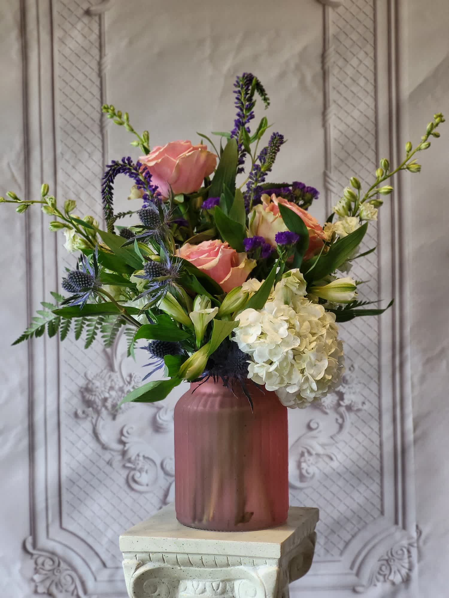 Pink roses and white hydrangea in a mauve vase