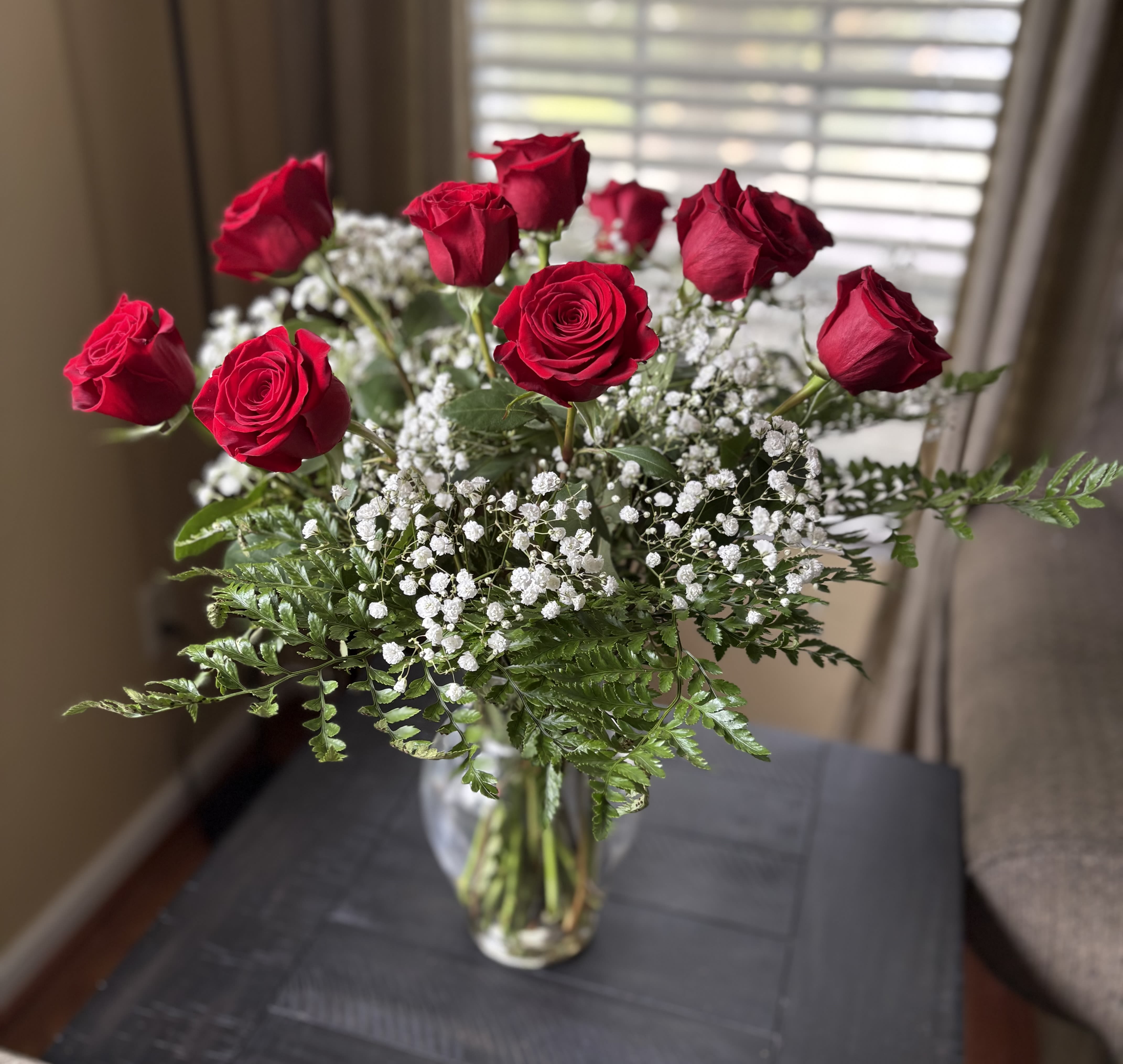 Red roses arranged in a clear glass vase with white baby's breath