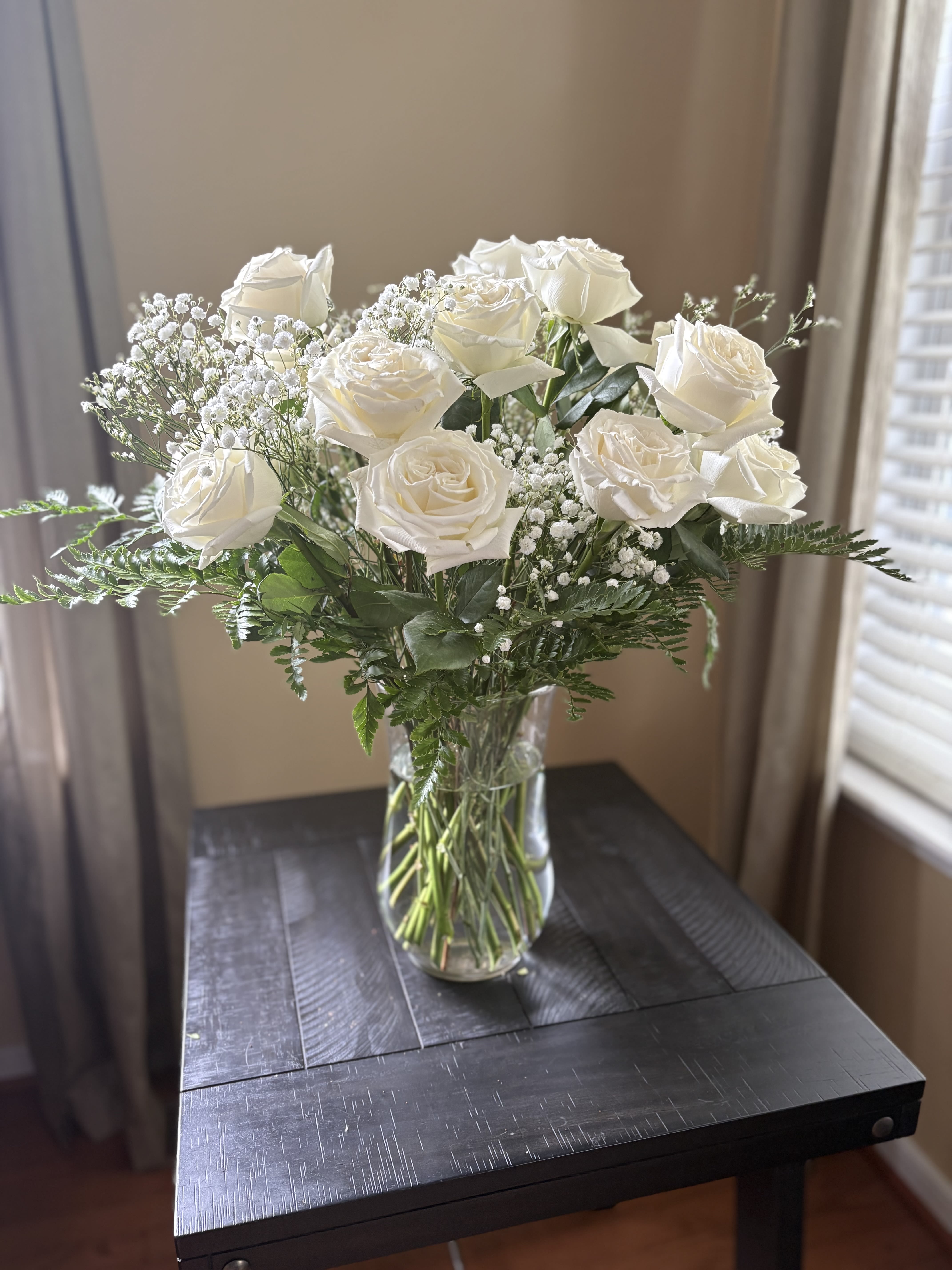 White roses arranged in a clear glass vase with baby's breath