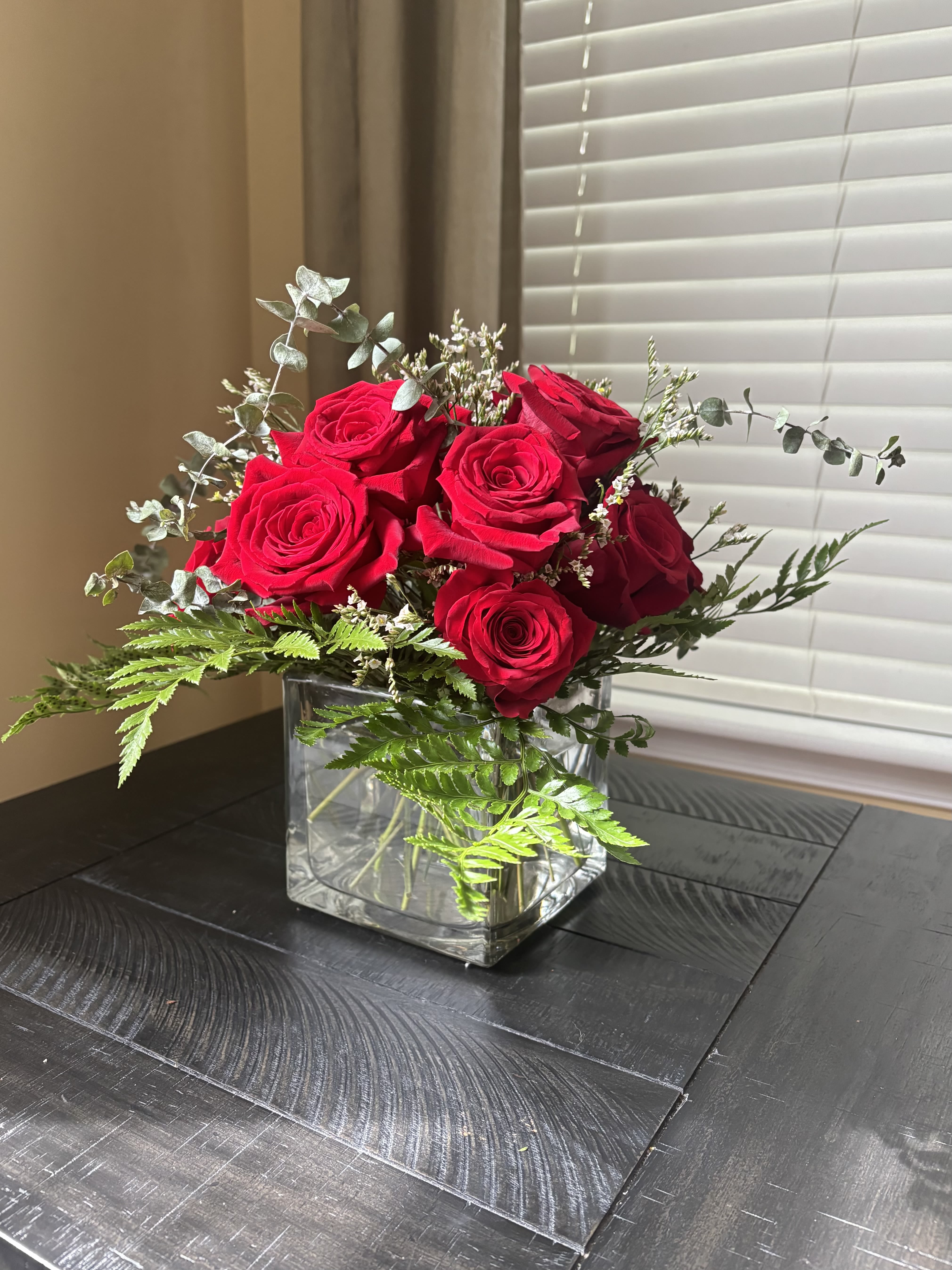 Red roses arranged in a clear square glass vase