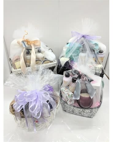 Four wrapped gift baskets with bath and body products and ribbons