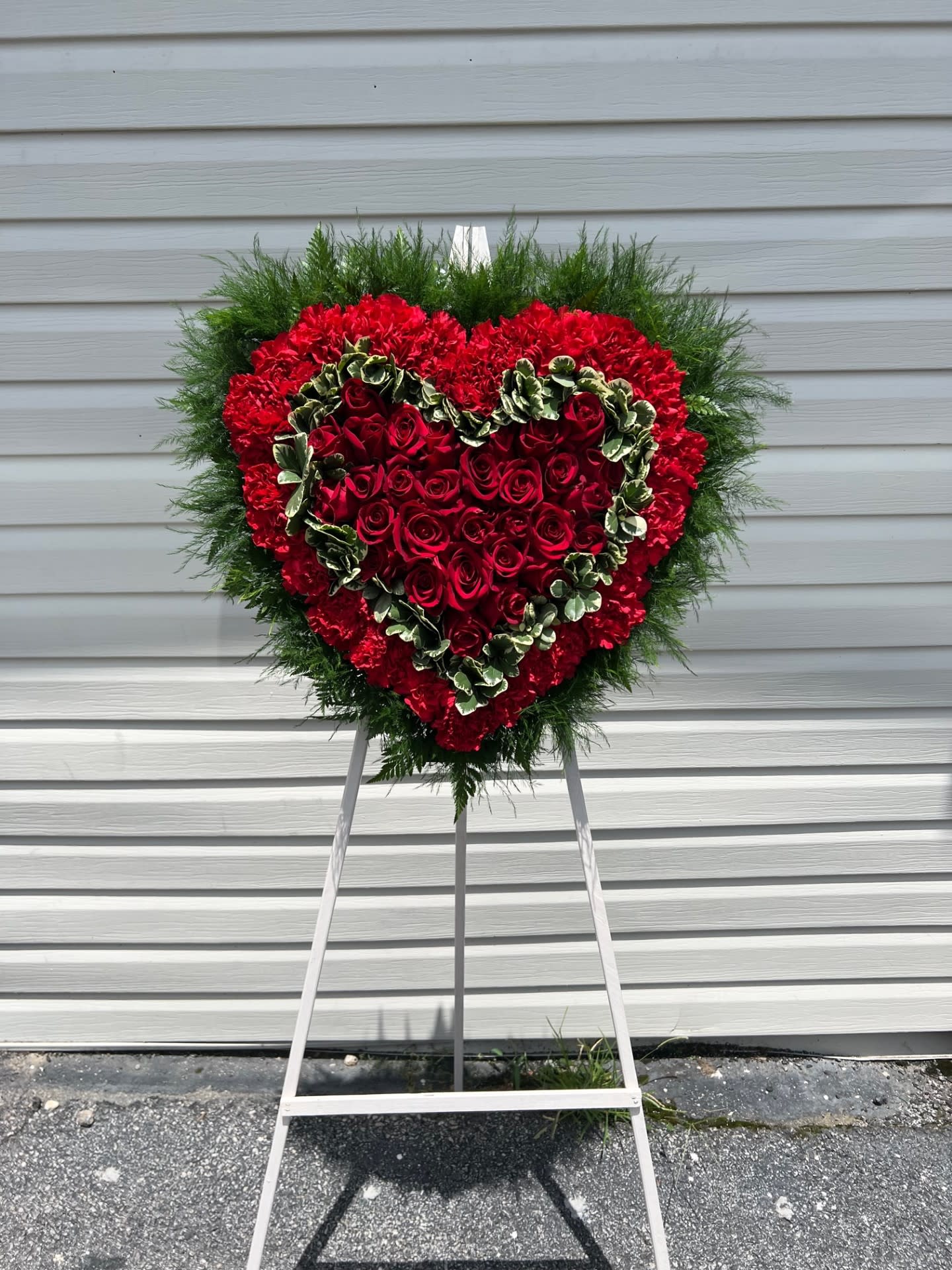 Heart-shaped red rose wreath on a standing easel