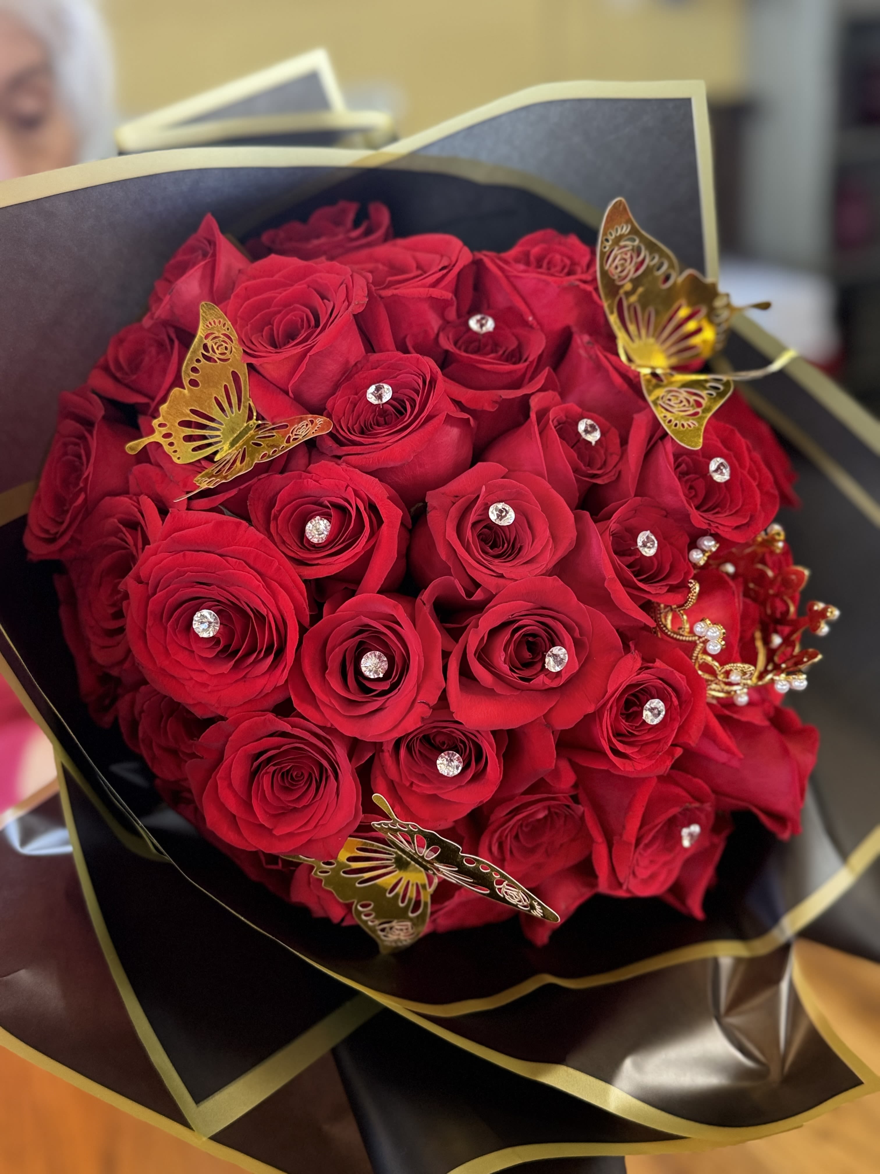 Bouquet of red roses with gold butterfly decorations and rhinestones