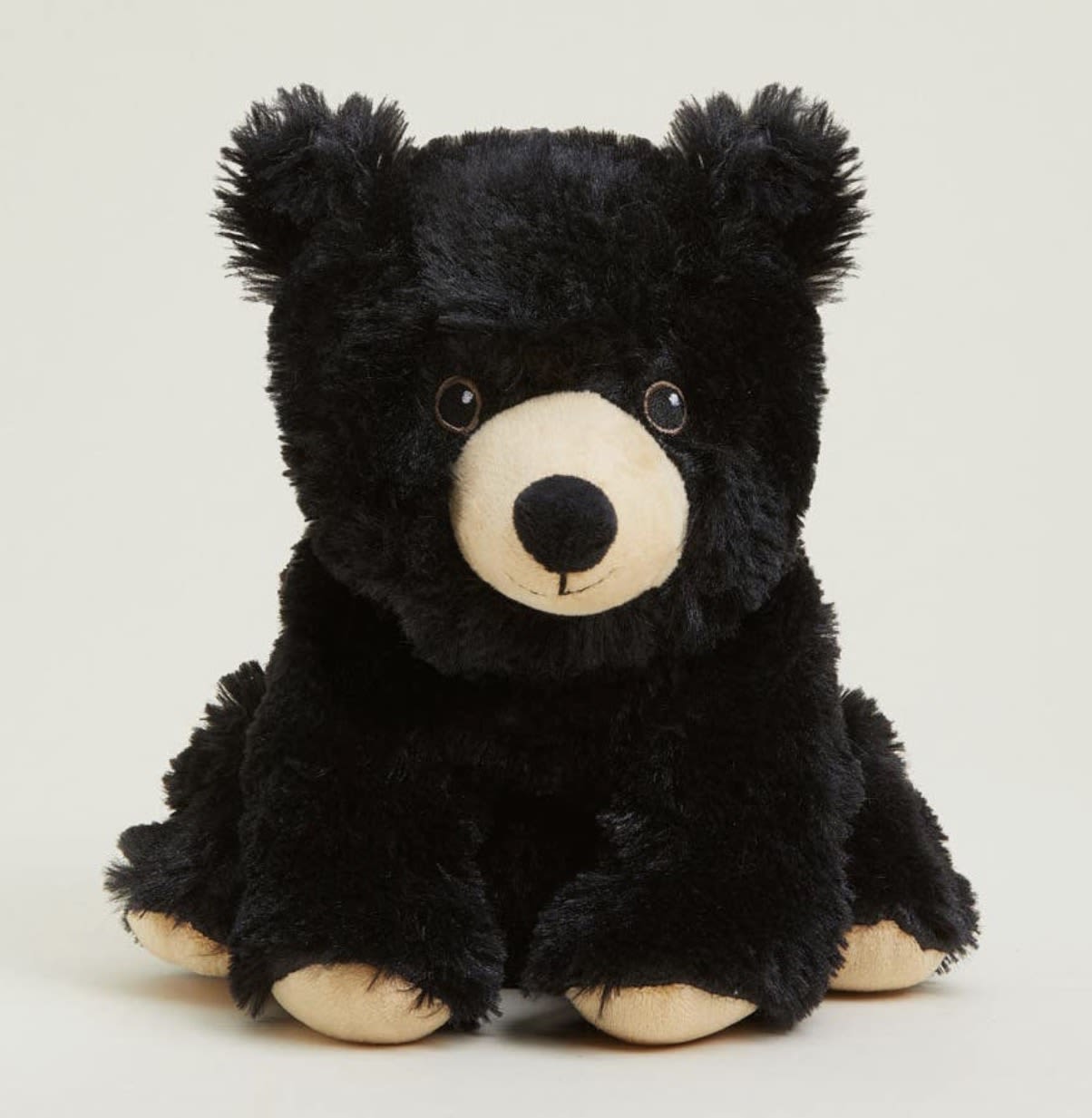 Black Bear Warmies  - A cuddly black plush teddy bear with cream-colored snout, inner ears, and paws makes a quietly comforting gift for birthdays, get-well wishes, or a "just because" surprise. This seated Warmies-style bear is soft and rounded, its gentle face and plush texture designed to make the person you're thinking of feel soothed and genuinely seen.  The bear measures as a small, easy-to-hold keepsake (ideal for bedside or lap), with contrasting black and cream fur that reads warm and neutral in any room. Pair it with a bouquet or send it solo as an add-on to brighten someone's day; its simple, classic look complements floral gifts without overpowering them. Care is easy-spot clean as needed and cuddle often.